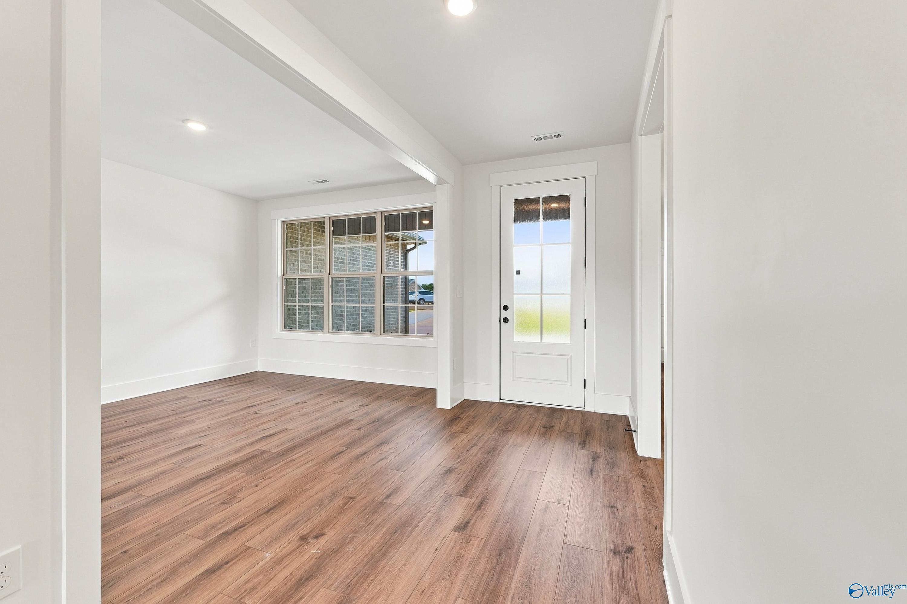 Bright entryway and dining area with luxury vinyl plank flooring, glass-panel front door, and large windows in Davidson Homes' Valencia floor plan at Riverton Preserve, Huntsville, Alabama.