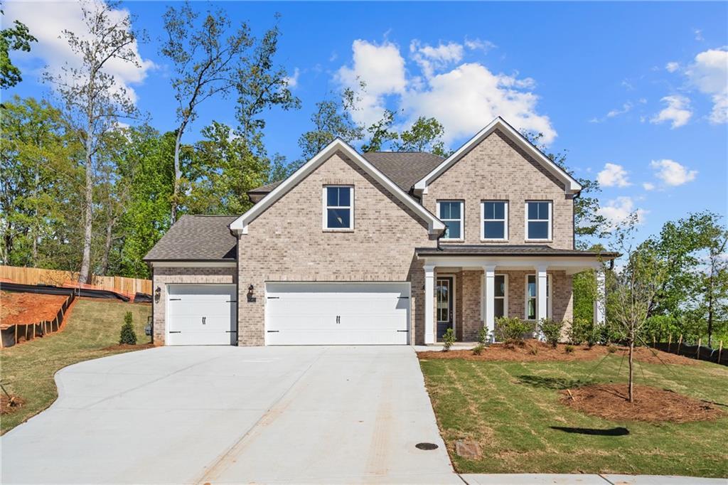 Two-story brick home with three-car garage, covered porch, and lush landscaping in Melody Lakeside Estates, Buford, Georgia