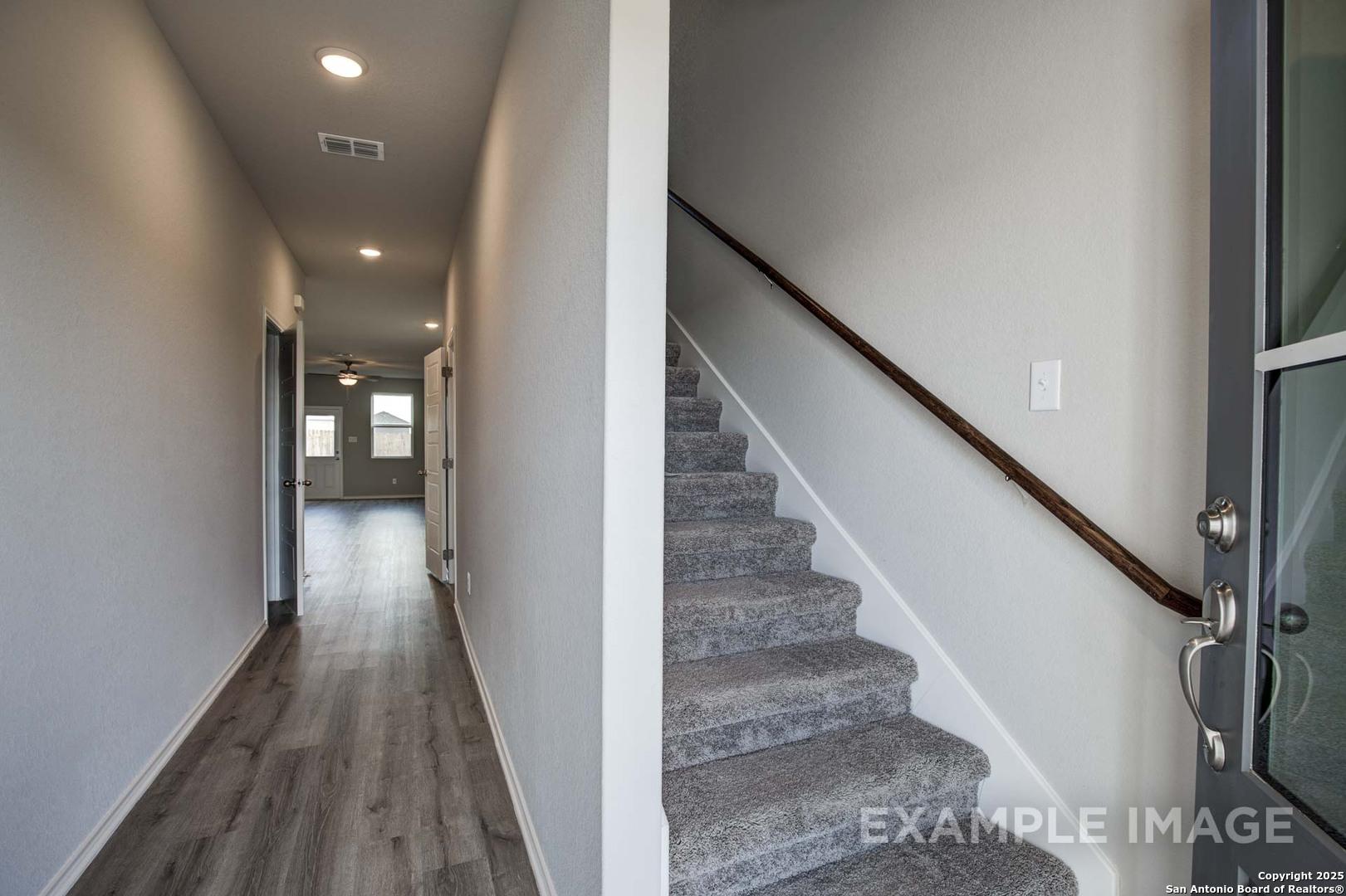 Bright hallway with luxury vinyl plank flooring and carpeted staircase in 2-story 4-bedroom Davidson Homes The Blanco C, Agave San Antonio