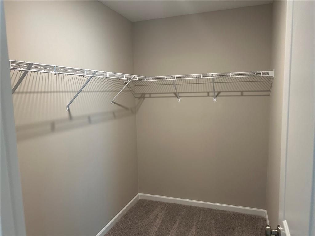 Spacious walk-in closet with white wire shelving and beige walls in Davidson Homes The Washington, Phenix City, Alabama