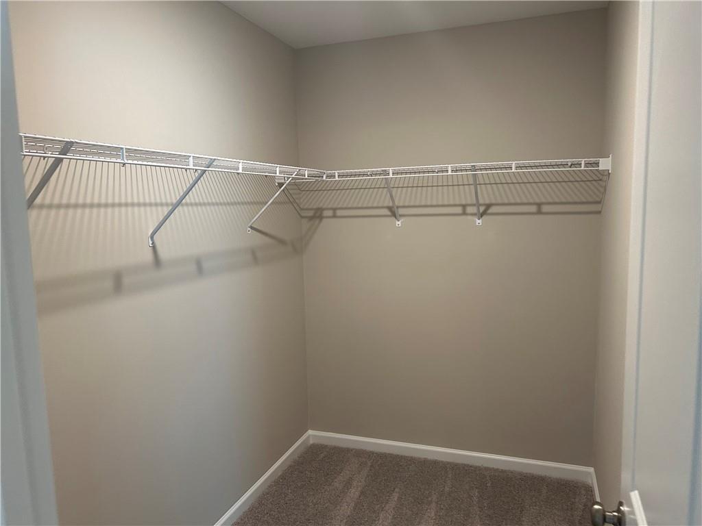Spacious walk-in closet with white wire shelving and beige walls in Davidson Homes The Washington, Phenix City, Alabama