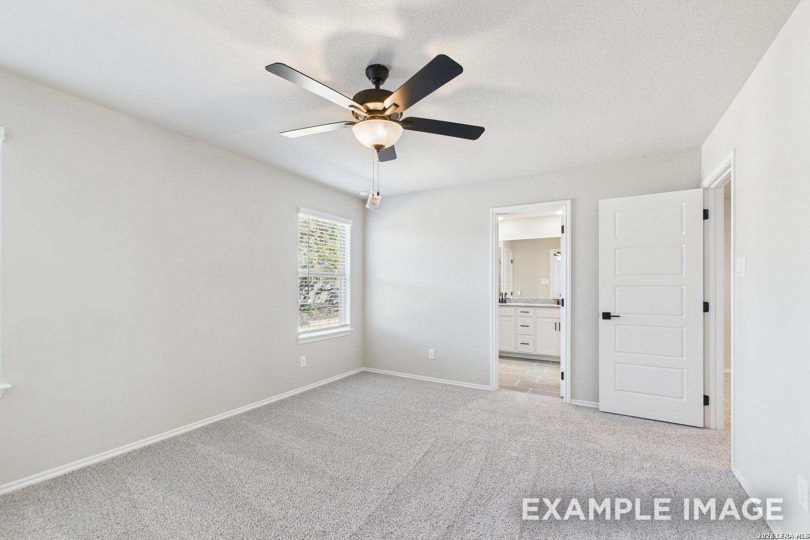 Bright bedroom with ceiling fan and en-suite bathroom in The Charlotte B floor plan by Davidson Homes in San Antonio, TX.