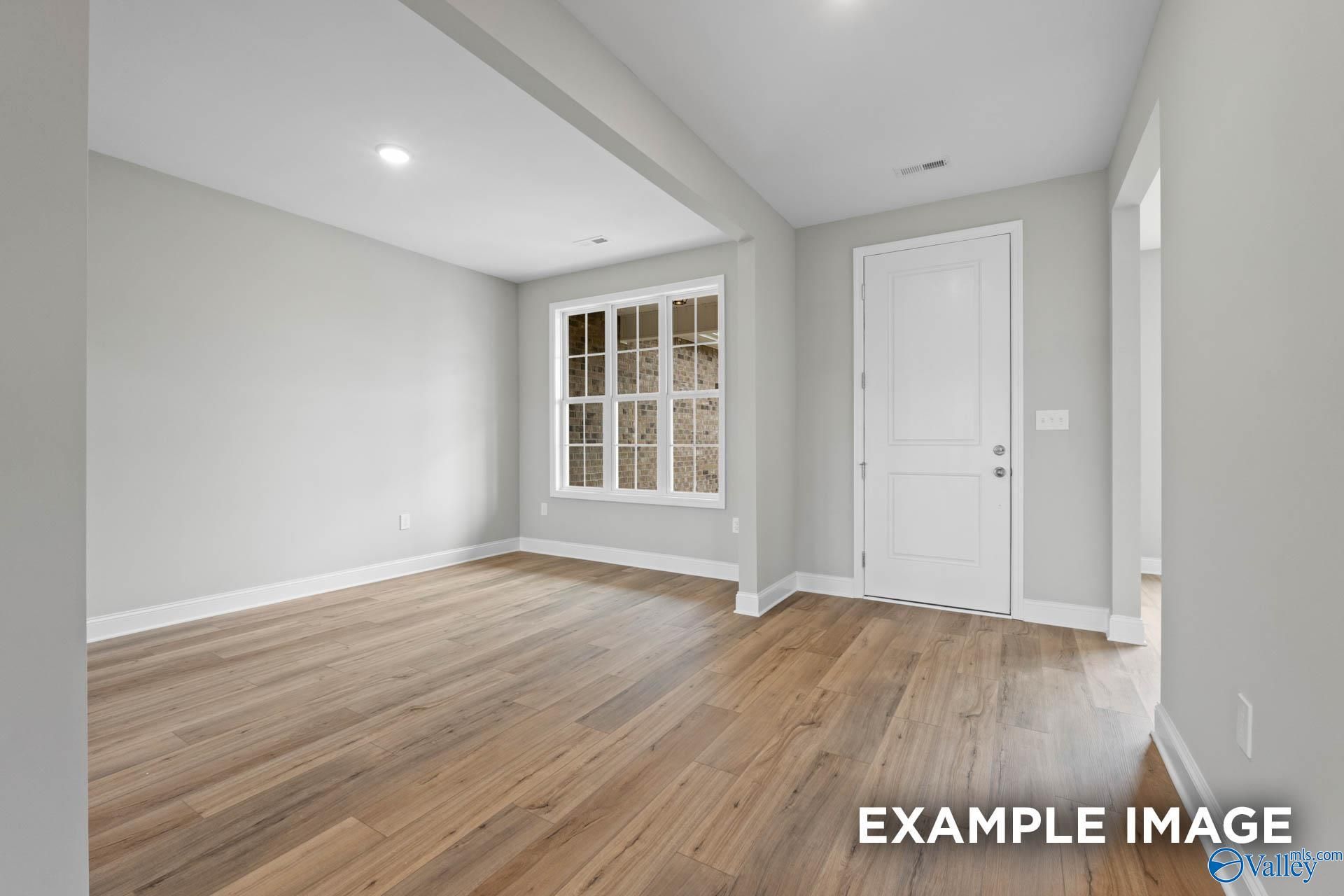 Bright open living room with light hardwood floors, large window, and gray walls in Davidson Homes The Finleigh, Creekside, Harvest, Alabama