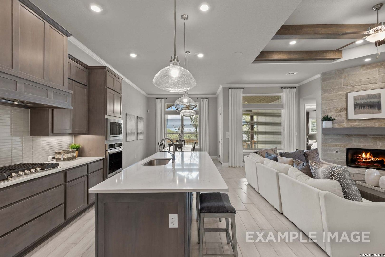 Open-concept kitchen and living area with stone fireplace in The Garner C floor plan at The Reserve at Potranco Oaks.