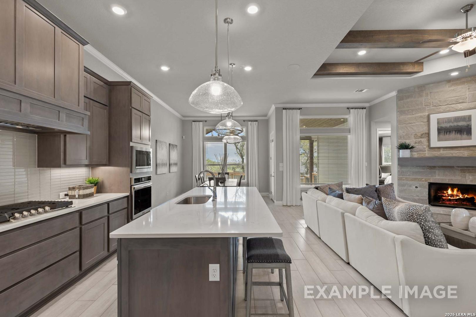 Open-concept kitchen and living area with stone fireplace in The Garner C floor plan at The Reserve at Potranco Oaks.