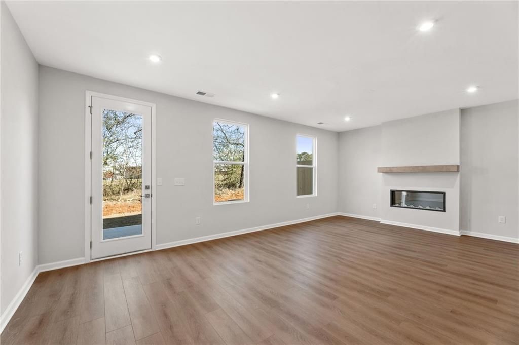 Cozy family room with modern gas fireplace, large windows, and sliding glass door to wooded backyard in Davidson Homes The Marion A, Winder, GA