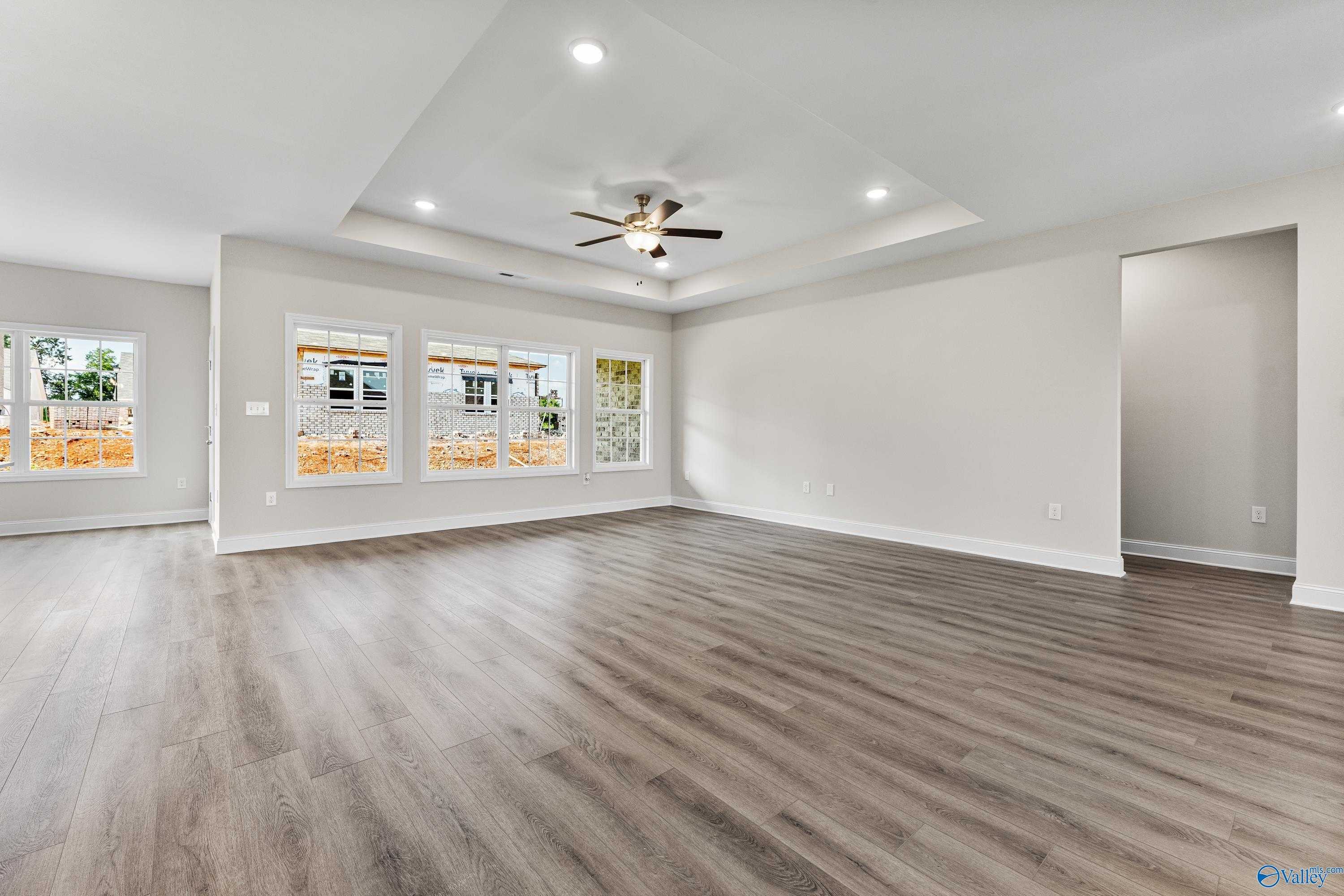 Bright spacious living room with hardwood floors, large windows, ceiling fan in Davidson Homes The Finleigh, Toney, Alabama