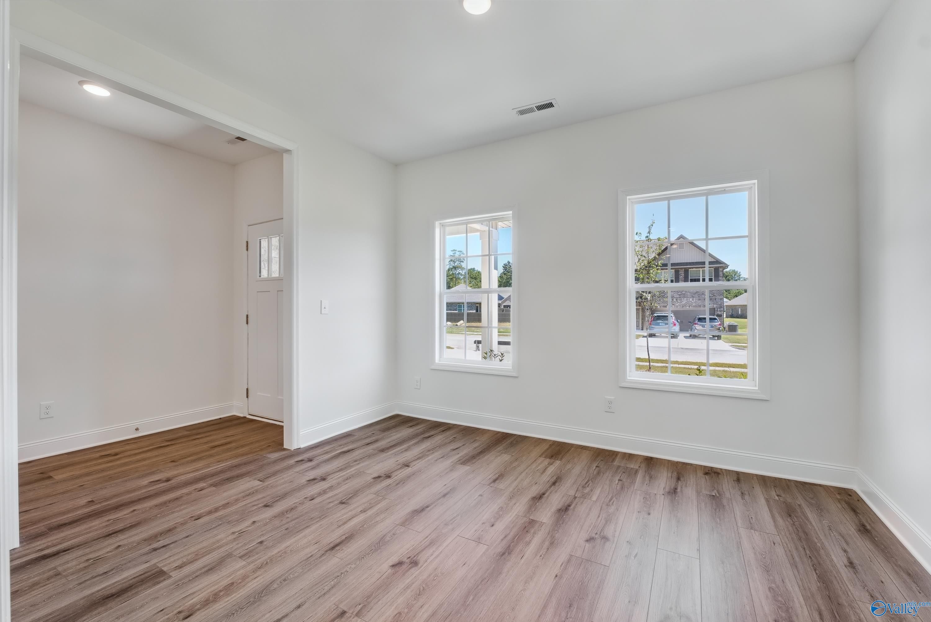 Bright bedroom with hardwood floors, white walls, and large windows in Davidson Homes The Shelby A, The Highlands, Arab, Alabama