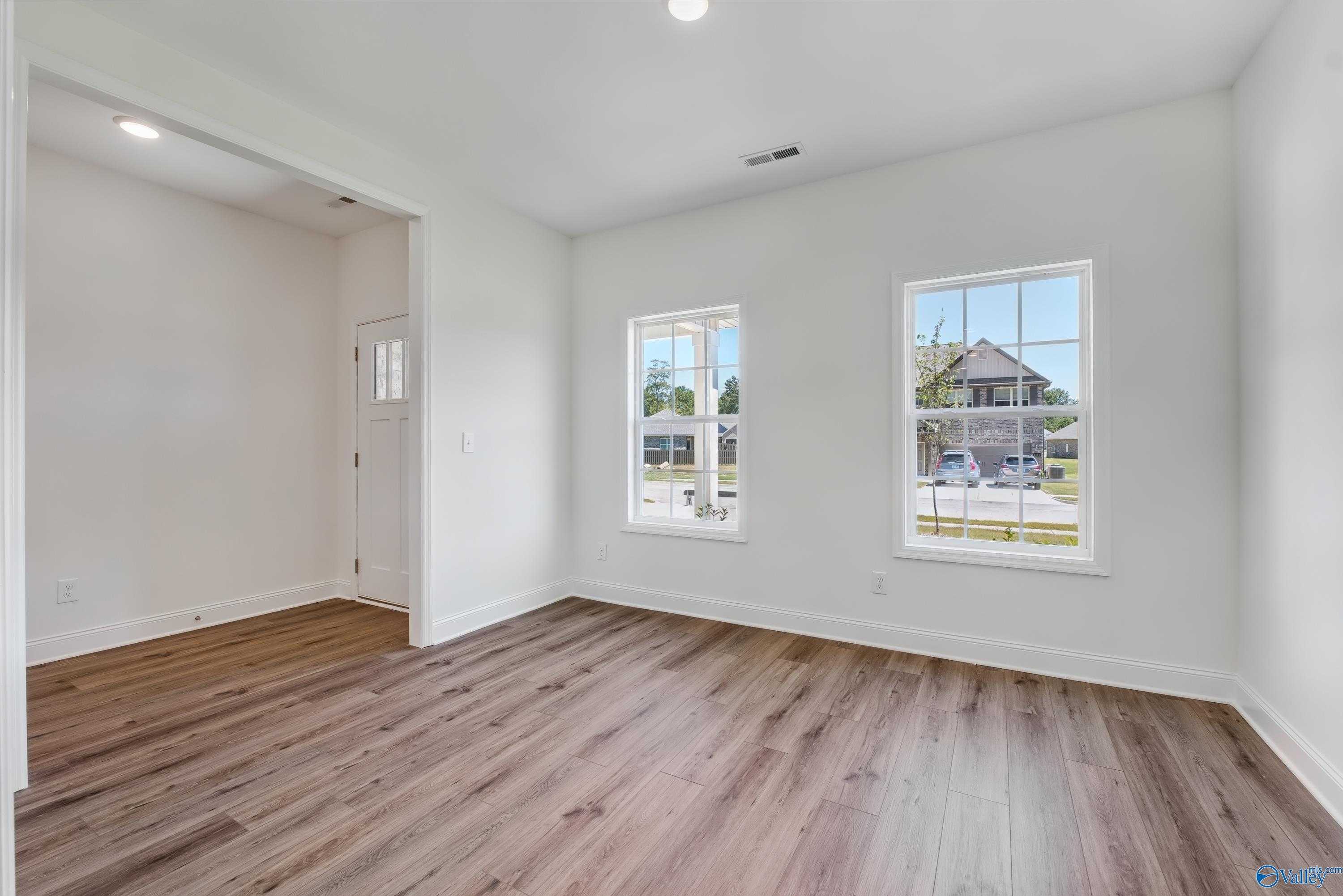 Bright bedroom with hardwood floors, white walls, and large windows in Davidson Homes The Shelby A, The Highlands, Arab, Alabama