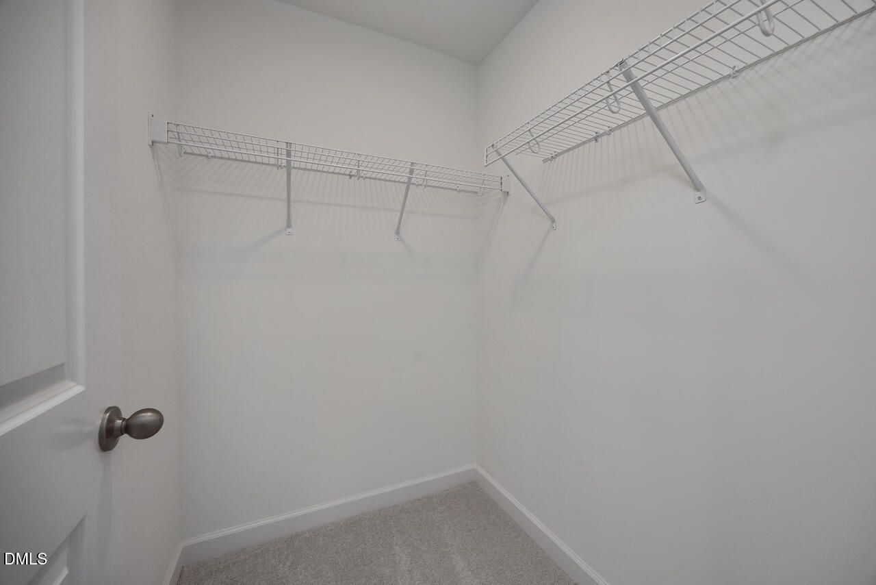 Walk-in closet with white wire shelving and carpet flooring in The Adalynn B floor plan at Gregory Village, Lillington.