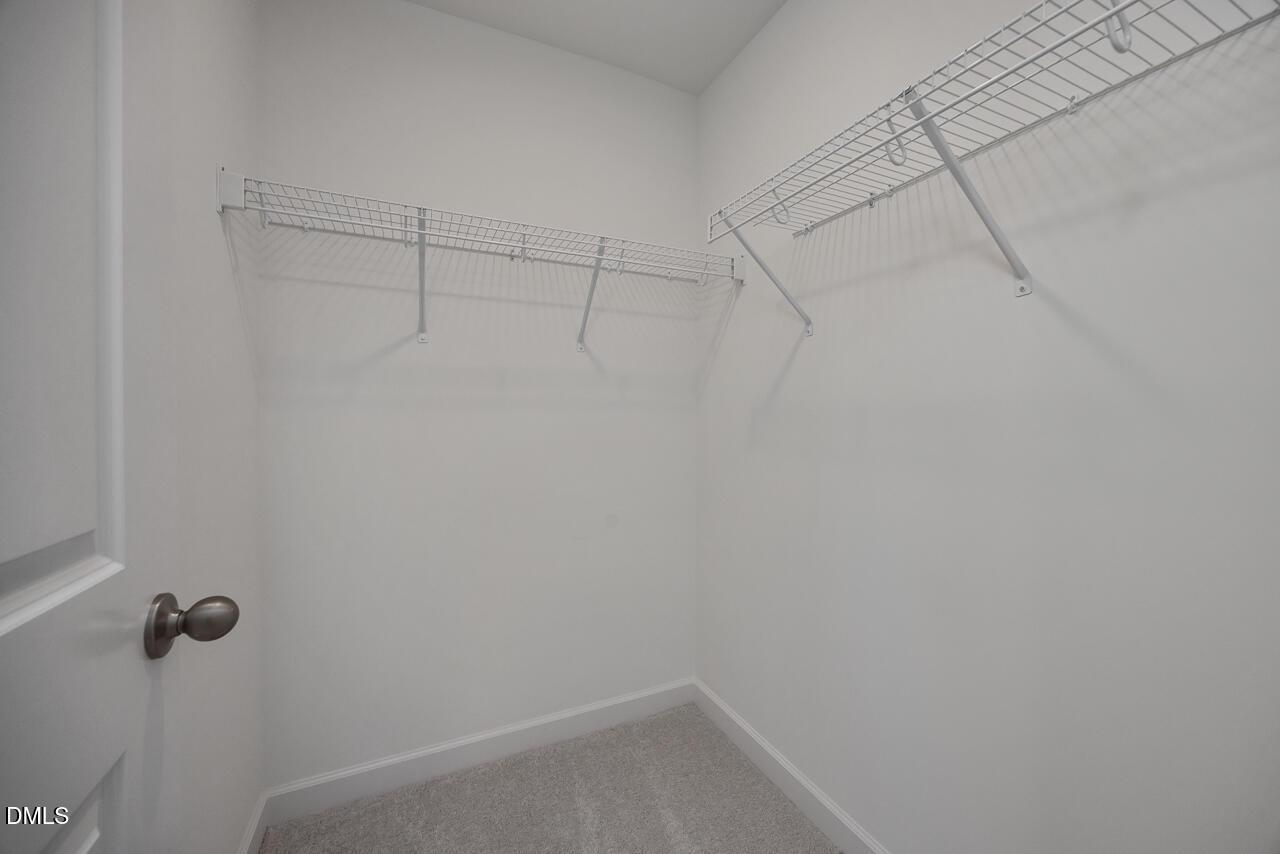 Walk-in closet with white wire shelving and carpet flooring in The Adalynn B floor plan at Gregory Village, Lillington.