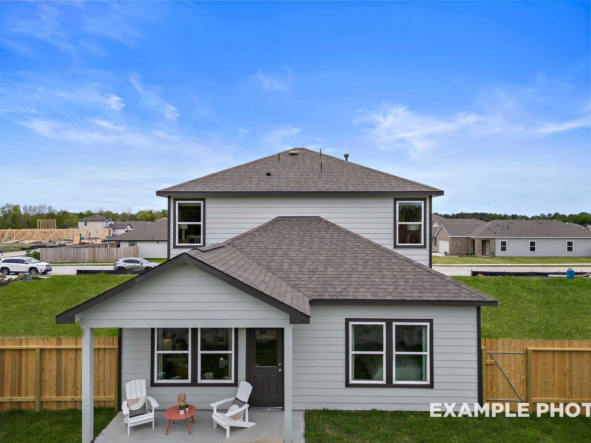 Two-story Sabine F home exterior with front porch, Adirondack chairs, and lush lawn in Windmill Estates, Magnolia, Texas