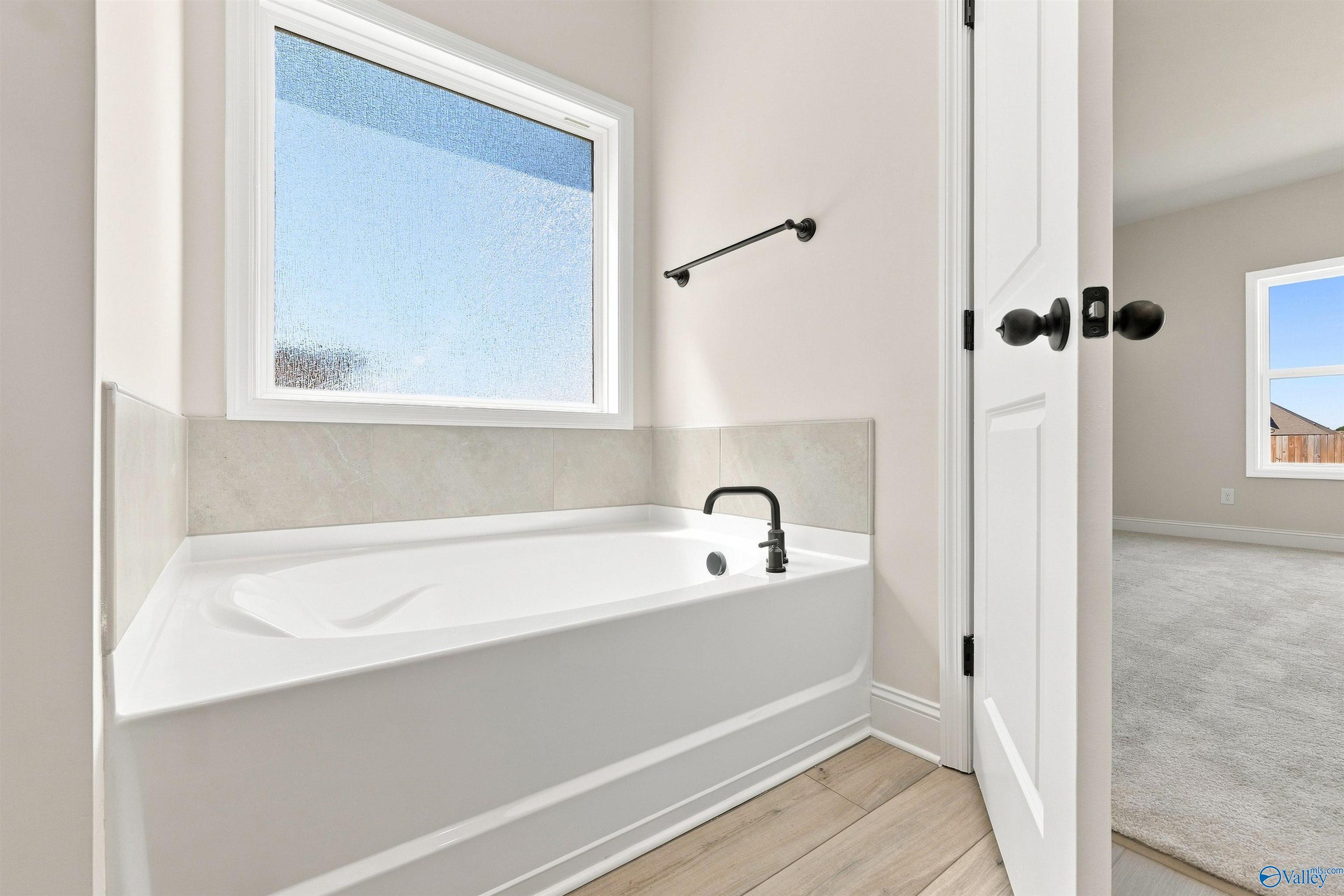 Soaking tub with matte black faucet beneath frosted window in master bath of Davidson Homes The Everett B, Ivy Hills, Toney AL