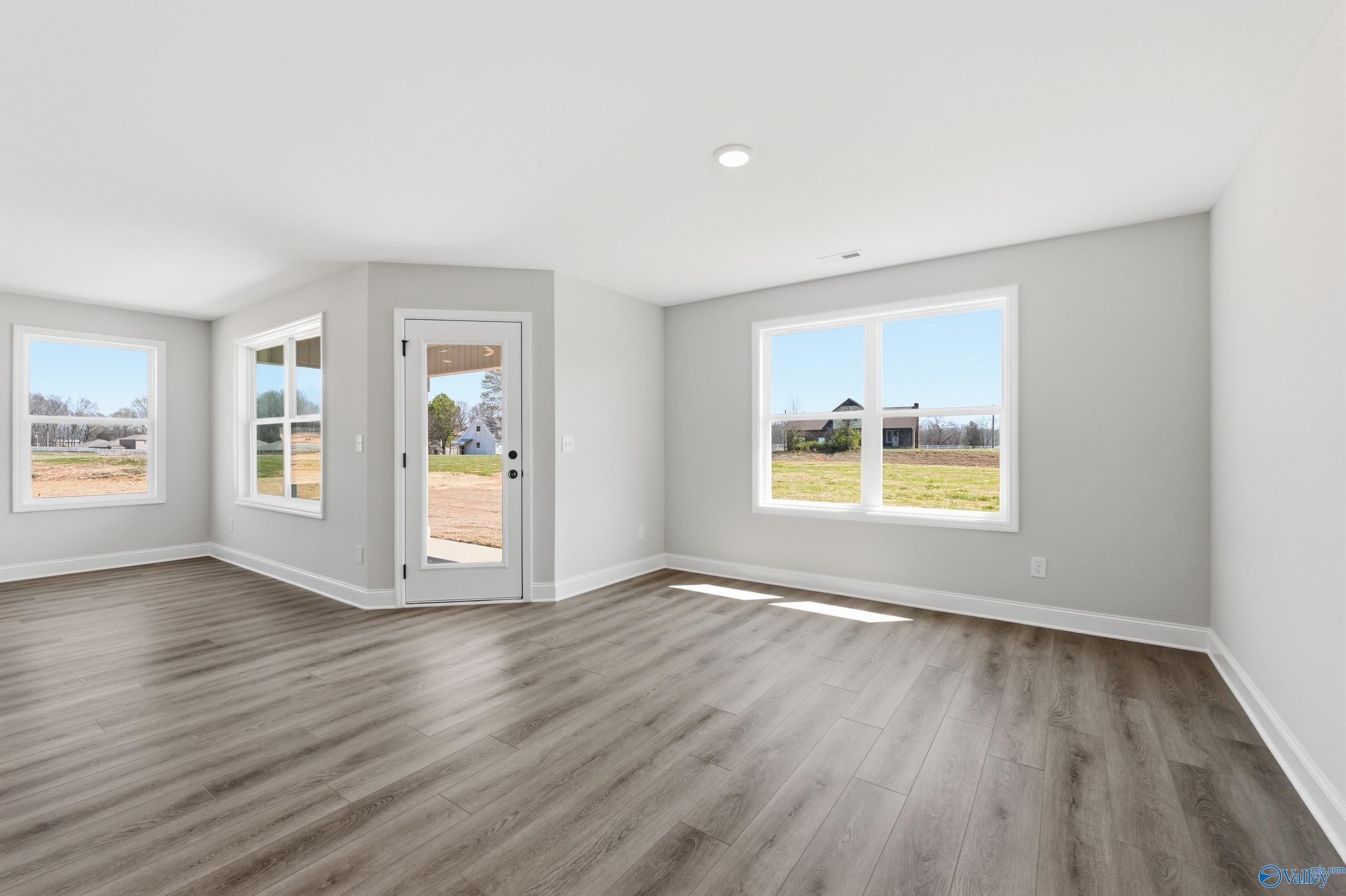 Spacious living room with large windows and rural views, hardwood floors in The Franklin V by Davidson Homes, Athens, AL
