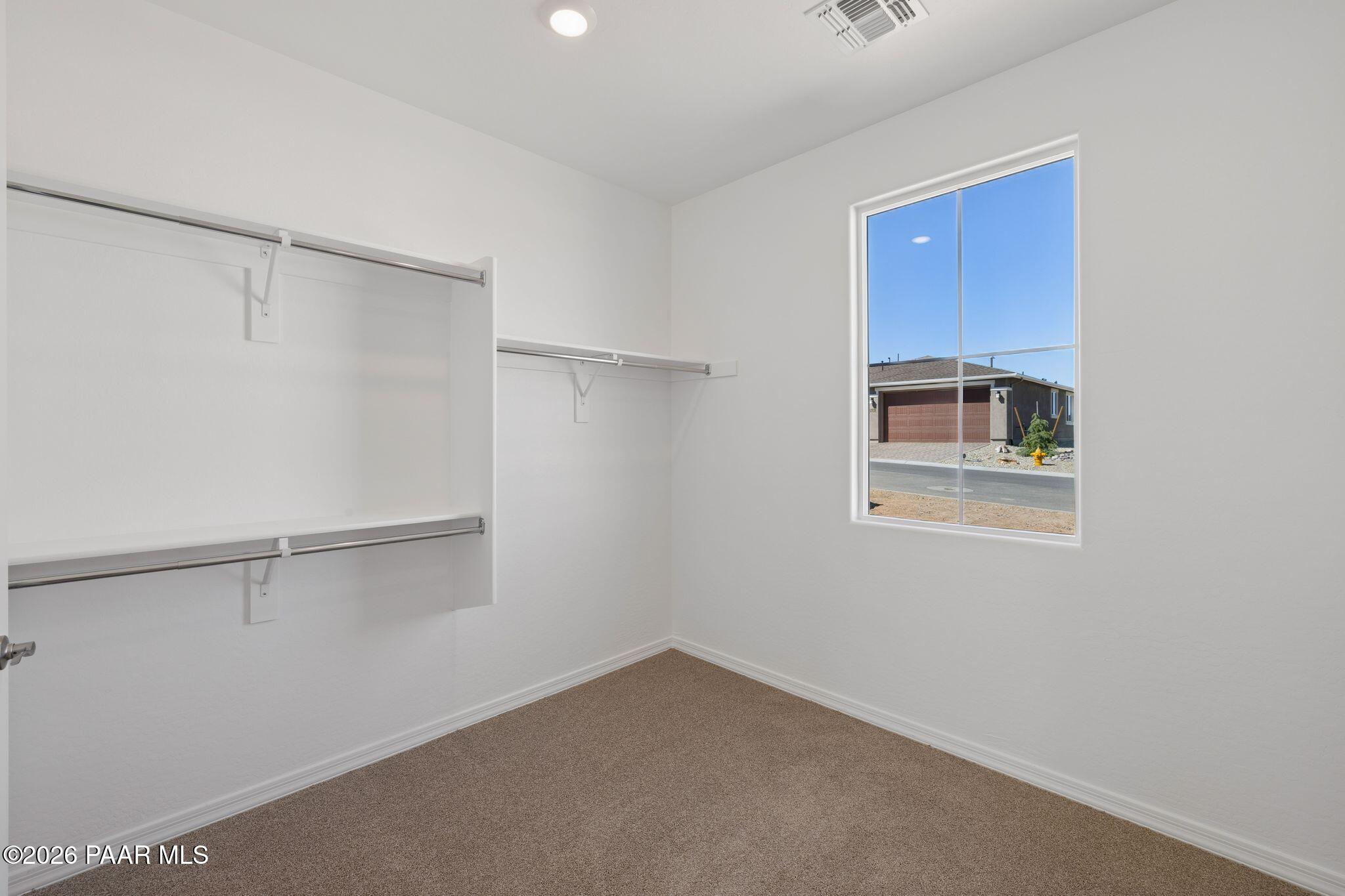 Spacious walk-in closet with built-in shelves, hanging rods, and large window overlooking garage in Davidson Homes The Monarch A, Prescott, Arizona
