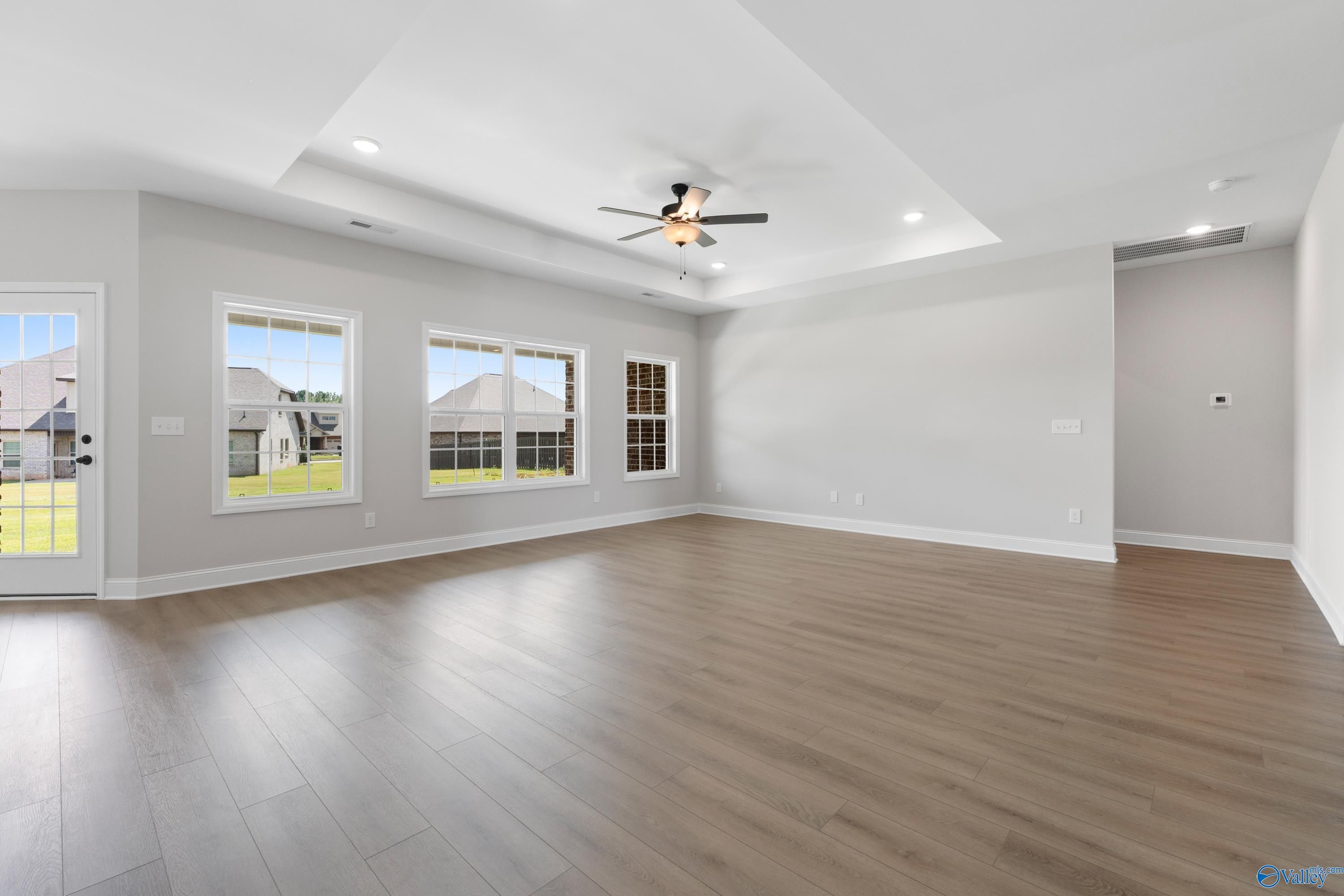 Spacious great room with vaulted ceiling, ceiling fan, large windows to yard in Davidson Homes The Rockford, Toney, Alabama