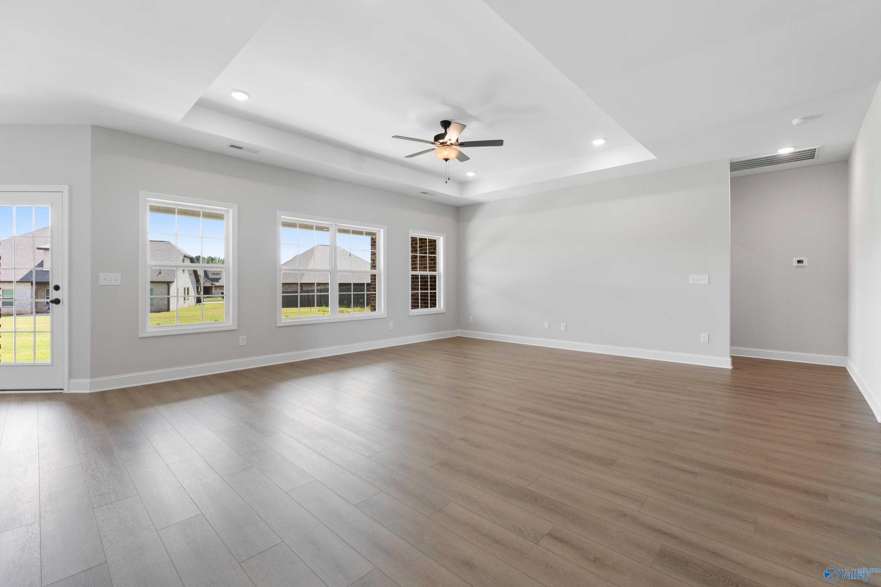 Spacious great room with vaulted ceiling, ceiling fan, large windows to yard in Davidson Homes The Rockford, Toney, Alabama