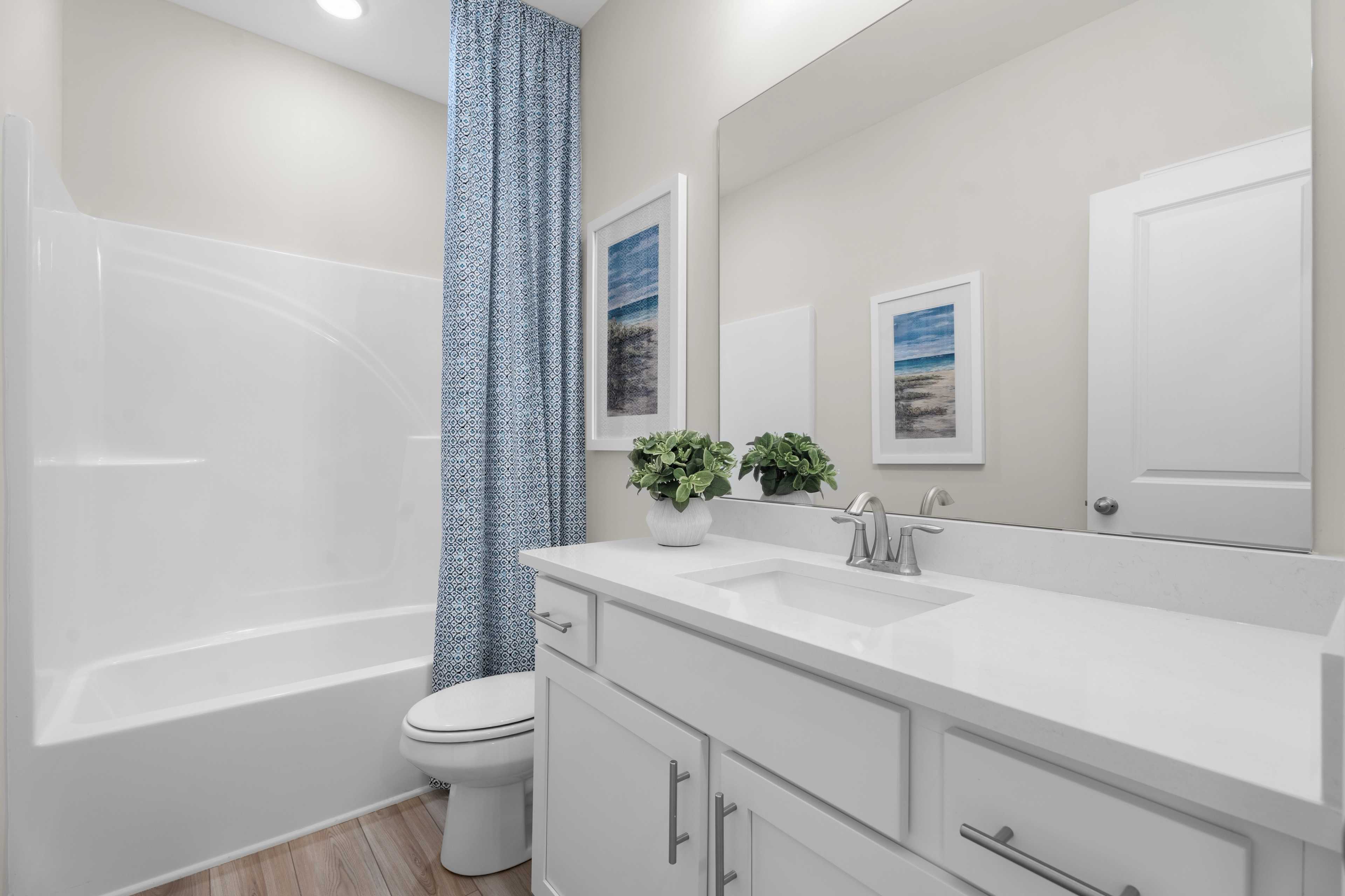Secondary bathroom with large countertop, single sink, bathtub shower combo, toilet