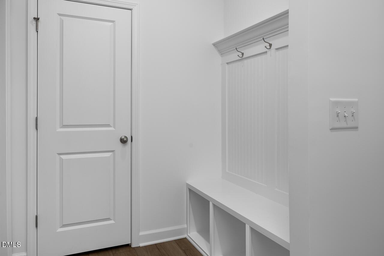 White mudroom with shaker door, beadboard walls, built-in bench, coat hooks in Davidson Homes The Cypress B II, Angier, NC