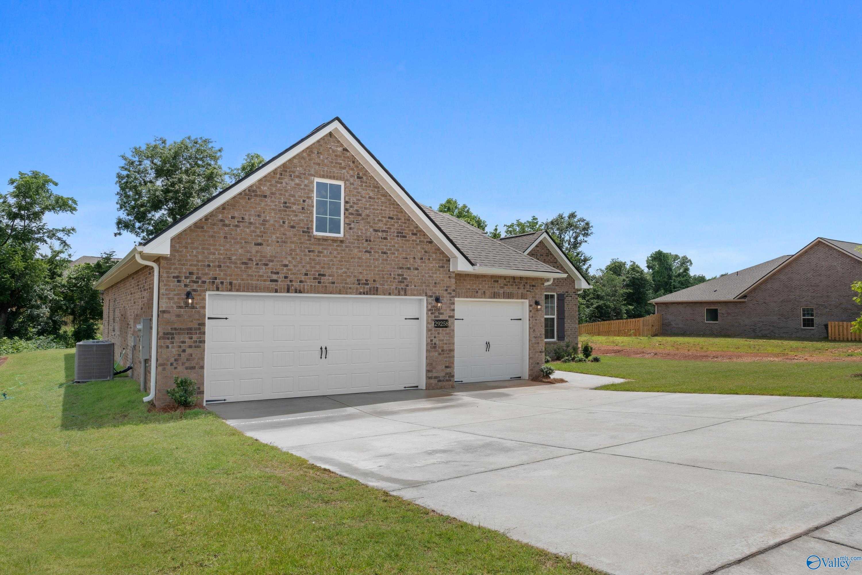 Modern brick 1-story home with 3-car garage, driveway, and lush landscaping in Creekside, Harvest, Alabama by Davidson Homes