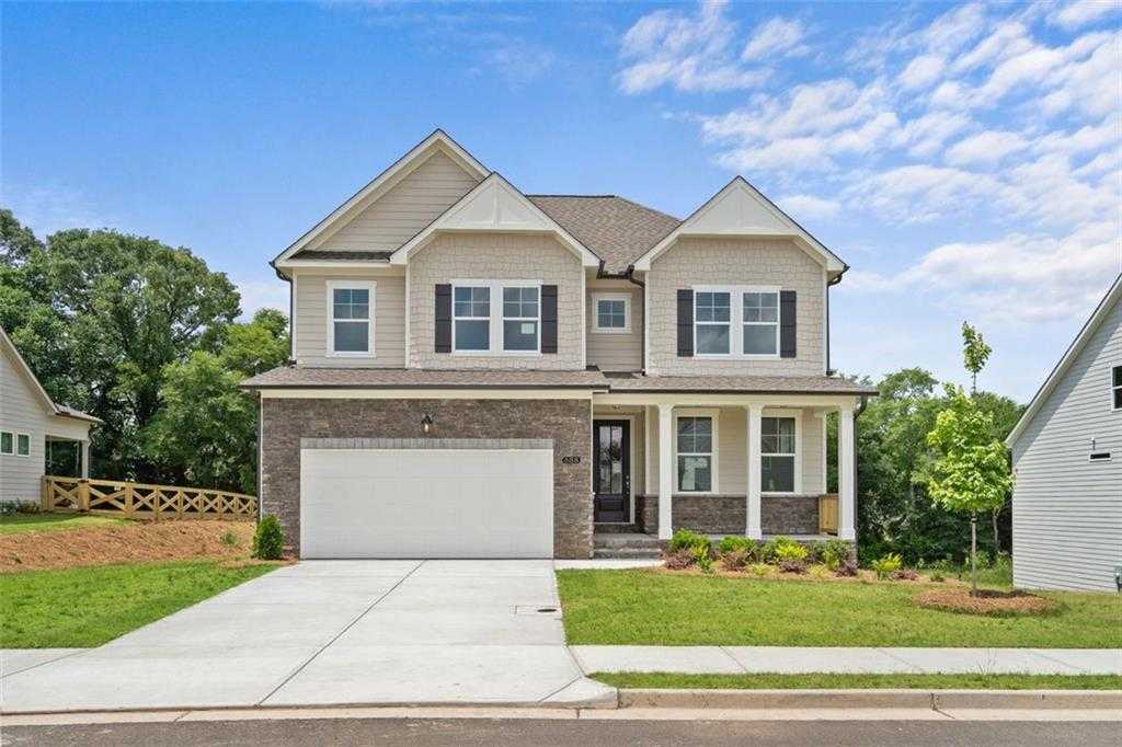 Modern 3-story tan home with brick accents, 2-car garage, and covered porch in Wehunt Meadows, Hoschton, Georgia