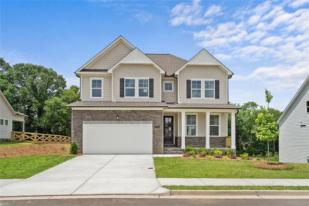 Modern 3-story tan home with brick accents, 2-car garage, and covered porch in Wehunt Meadows, Hoschton, Georgia