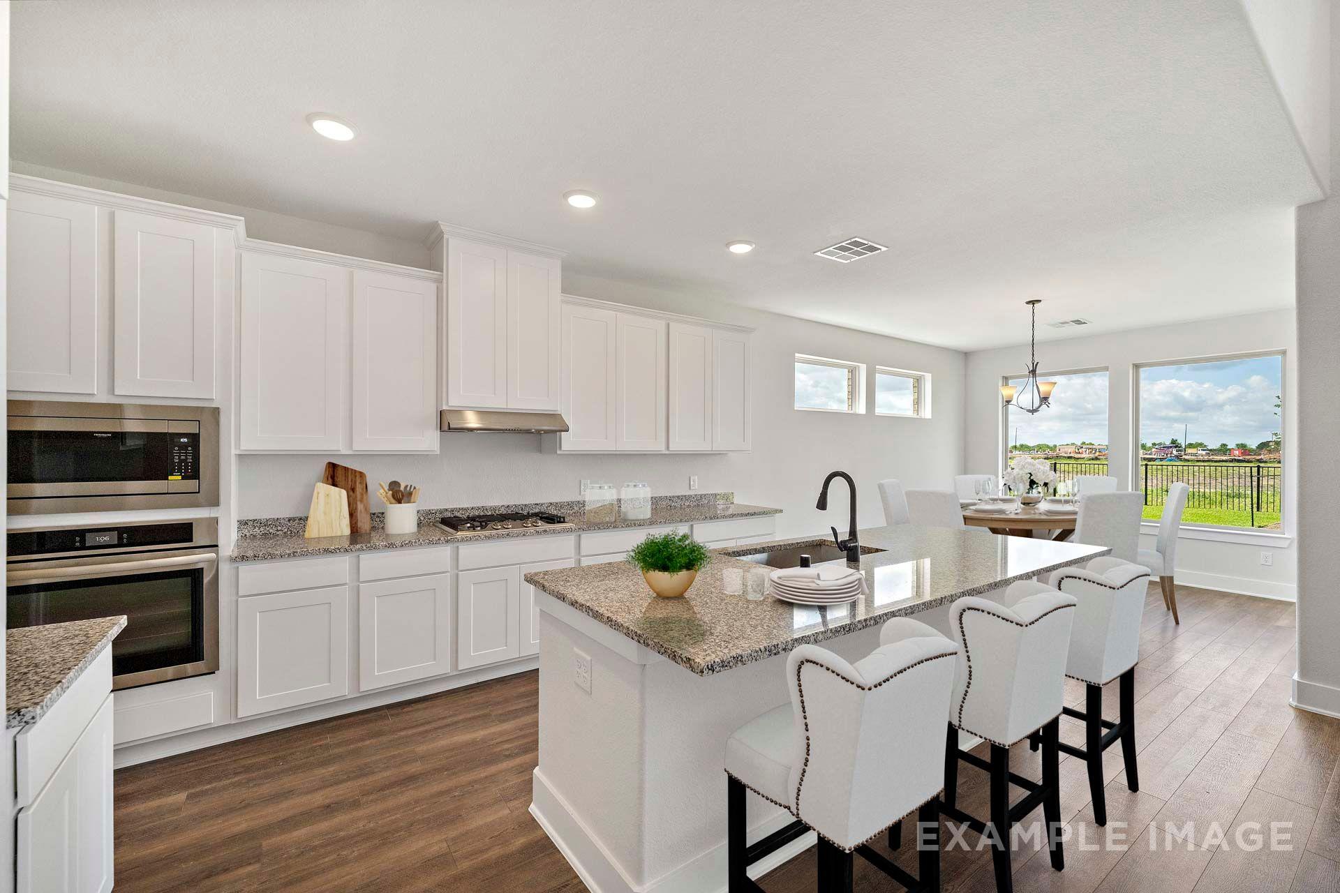 Bright white kitchen in The Victoria by Davidson Homes with granite island, breakfast bar, and open dining area