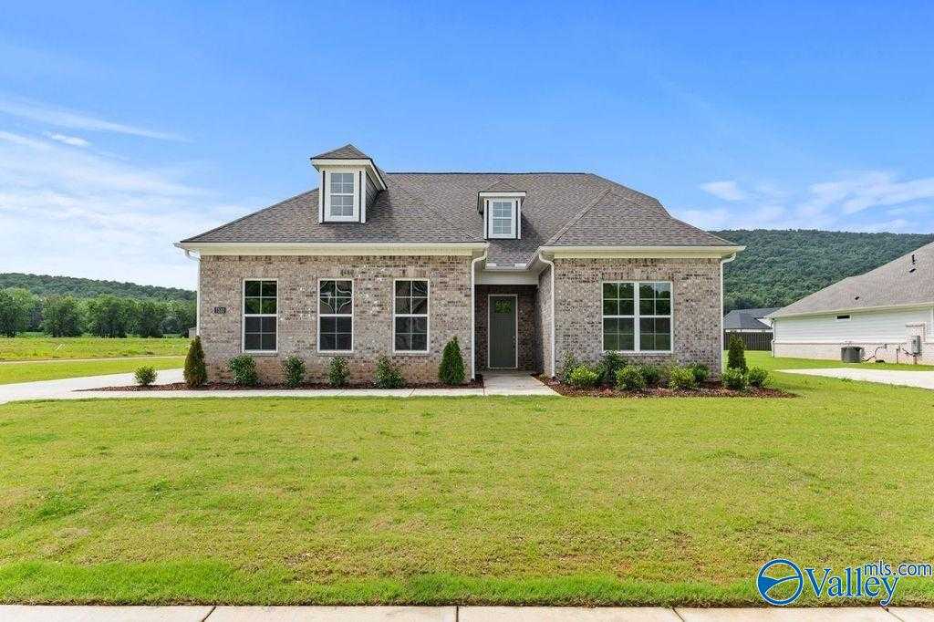 Charming 1.5-story brick home with dormer roof, large windows, and landscaped front yard in The Meadows at Hampton Cove, Owens Cross Roads, Alabama