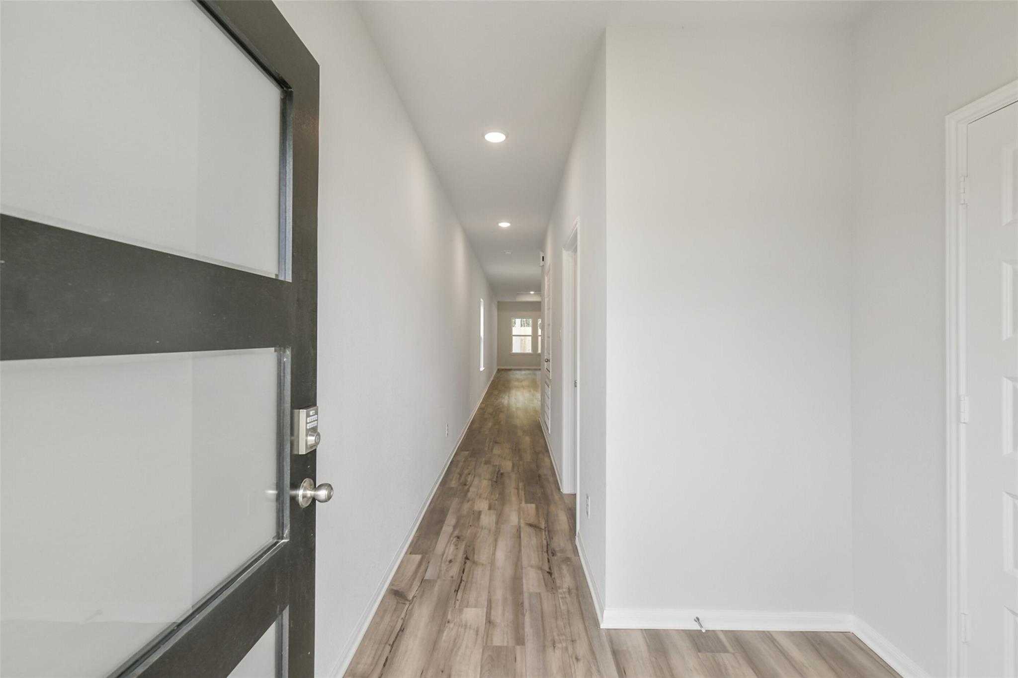 Modern entry hallway with frosted glass door, white walls, and hardwood floors in Davidson Homes The Frio G, Conroe, Texas