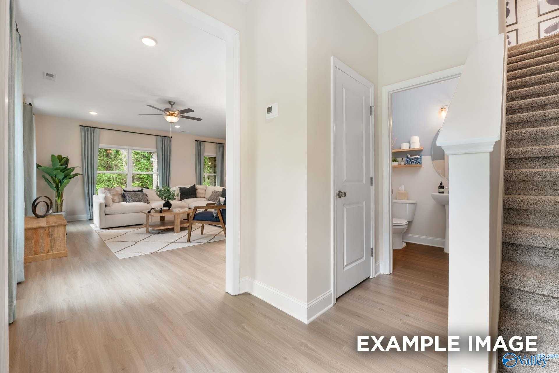 Bright open foyer with carpeted staircase, powder room, and cozy living room in Davidson Homes The Camden B, Huntsville AL