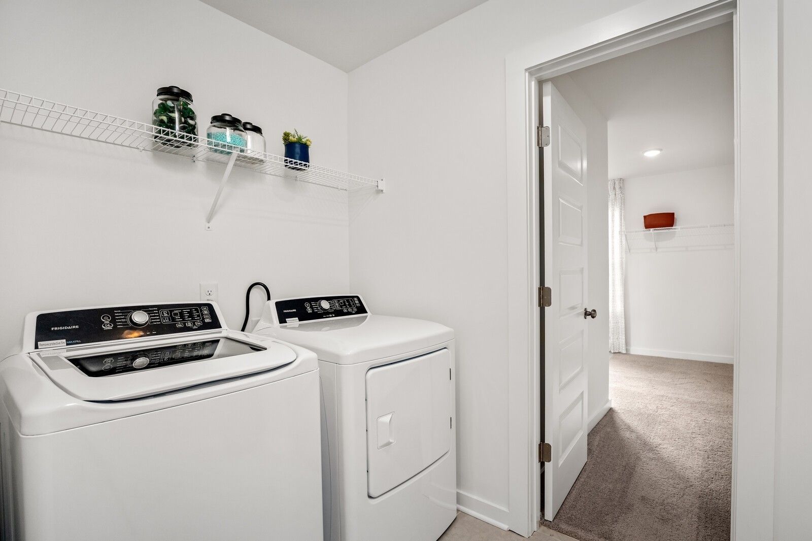 Laundry room with white appliances and wire shelving in The Gordon C floor plan at Sage Farms, White House, Tennessee.