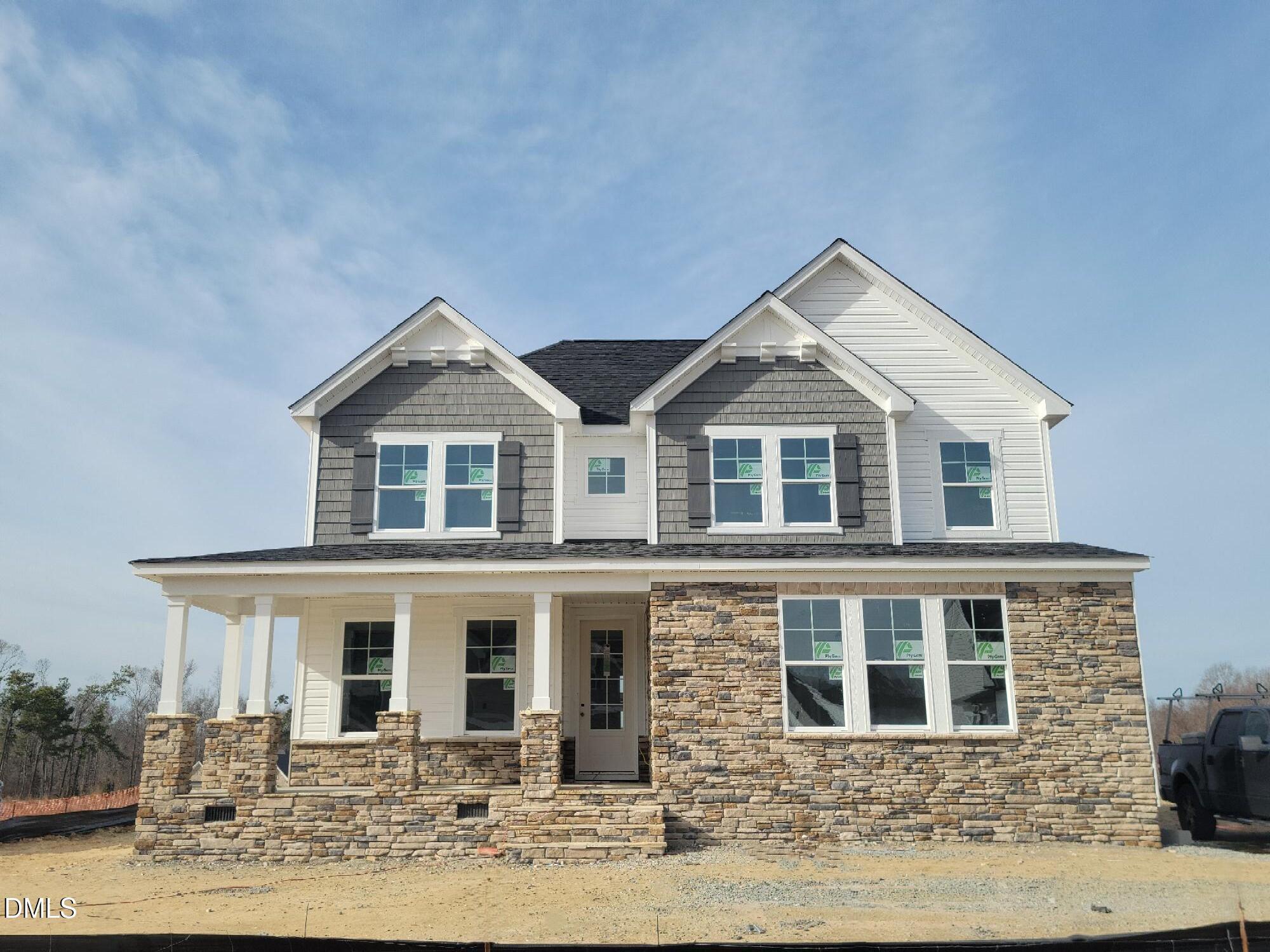 Modern two-story home with gray siding, stone base, covered porch, and large windows in Tobacco Road, Angier, NC - Davidson Homes Willow G