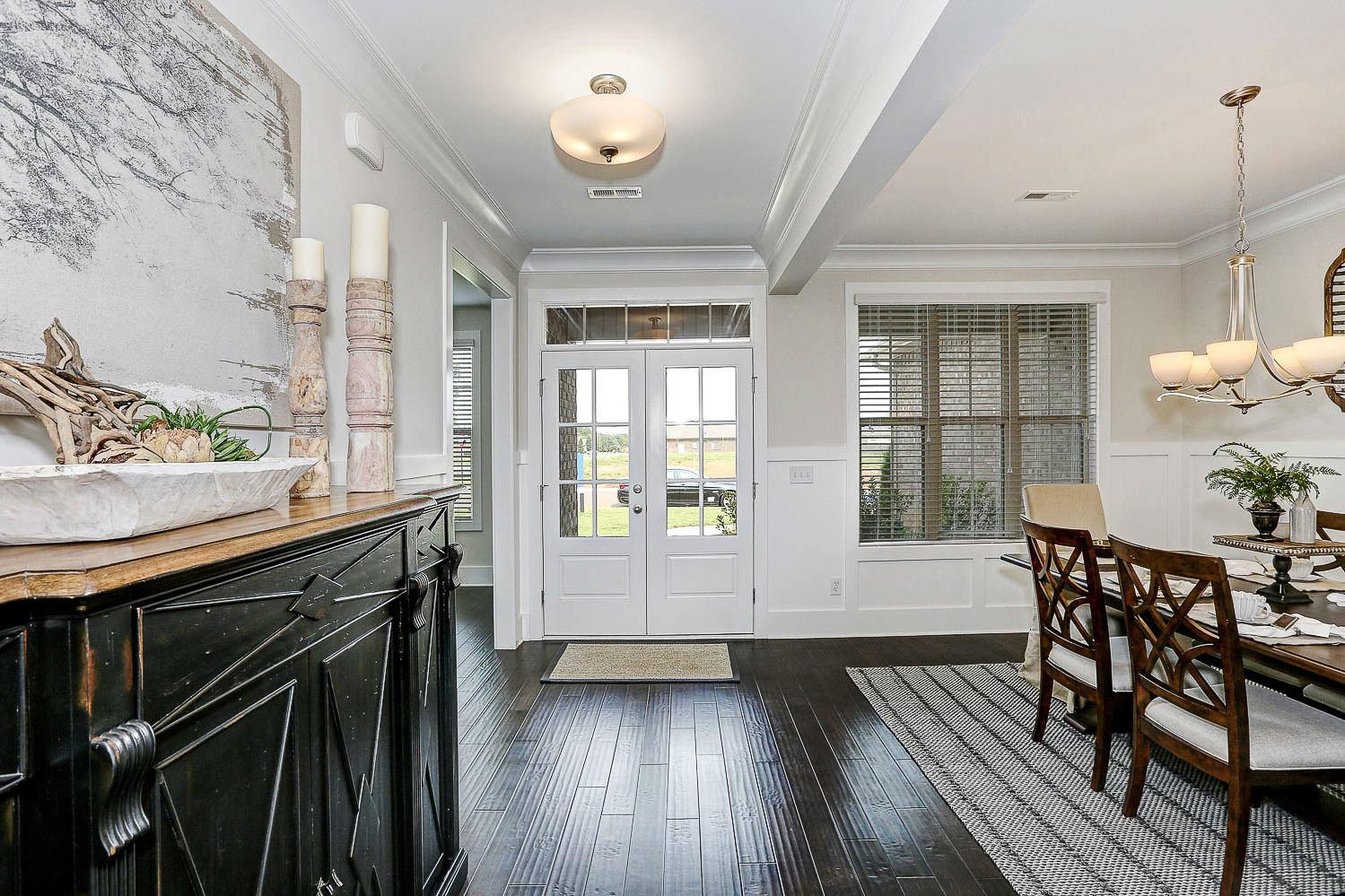 Spacious hallway opening to dining room in The Finleigh Davidson Homes design with hardwood floors, black buffet, and chandelier