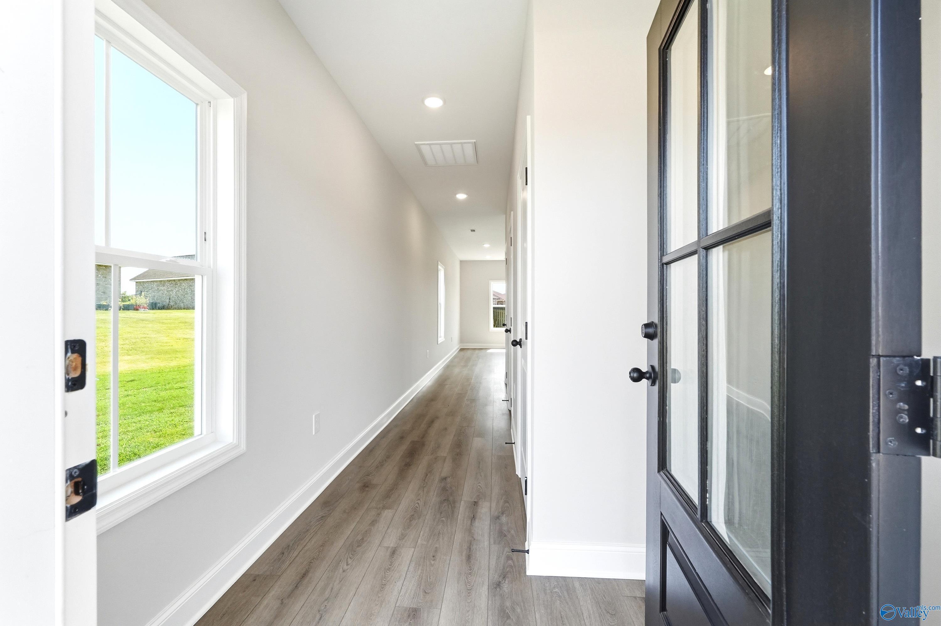 Bright, modern hallway with wood-style flooring in The Burton B floor plan at Heritage Lakes in New Market, Alabama.