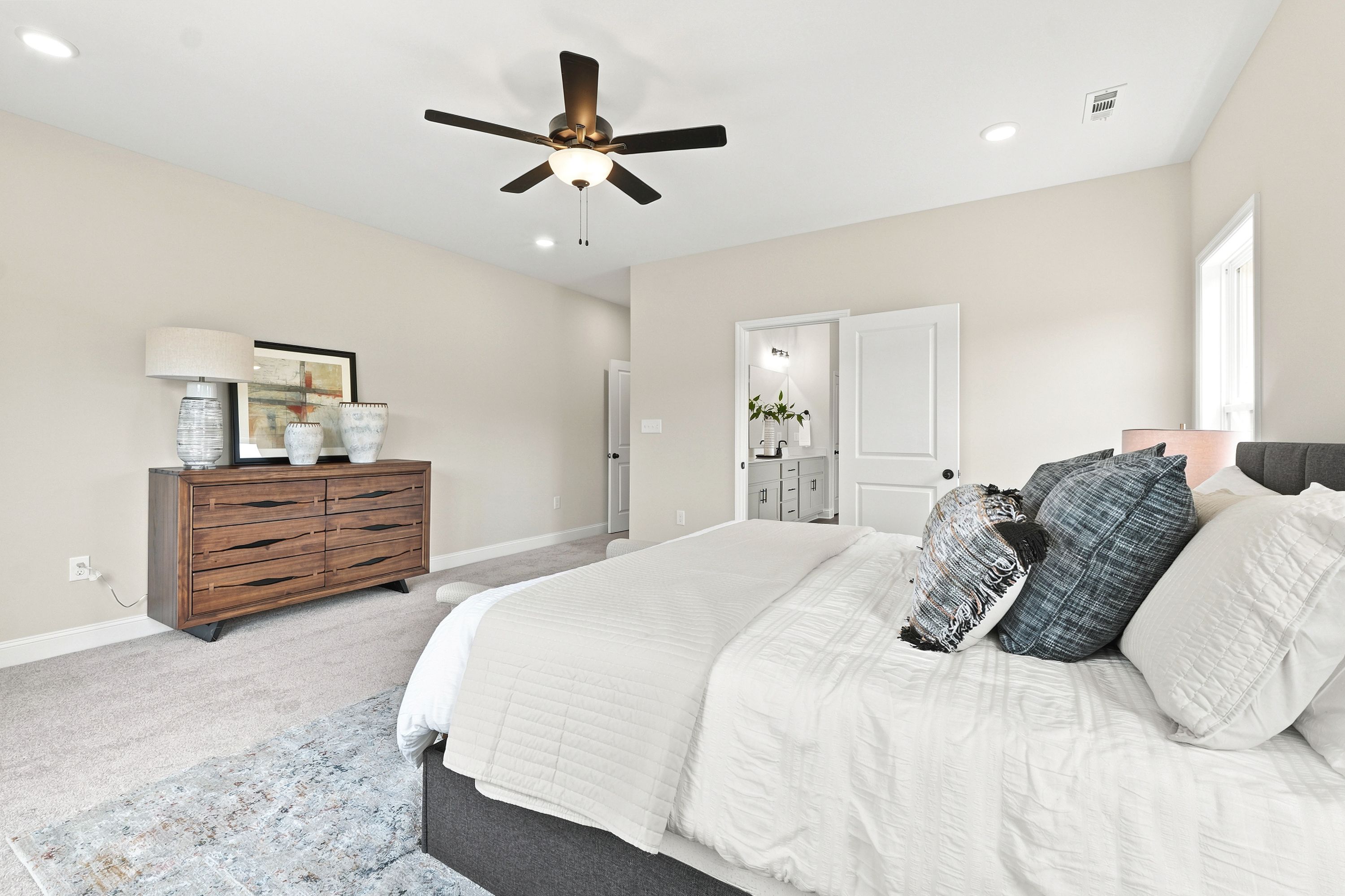 Spacious primary bedroom at Riverton Preserve in Huntsville, AL by Davidson Homes featuring a modern dresser and ensuite bath.