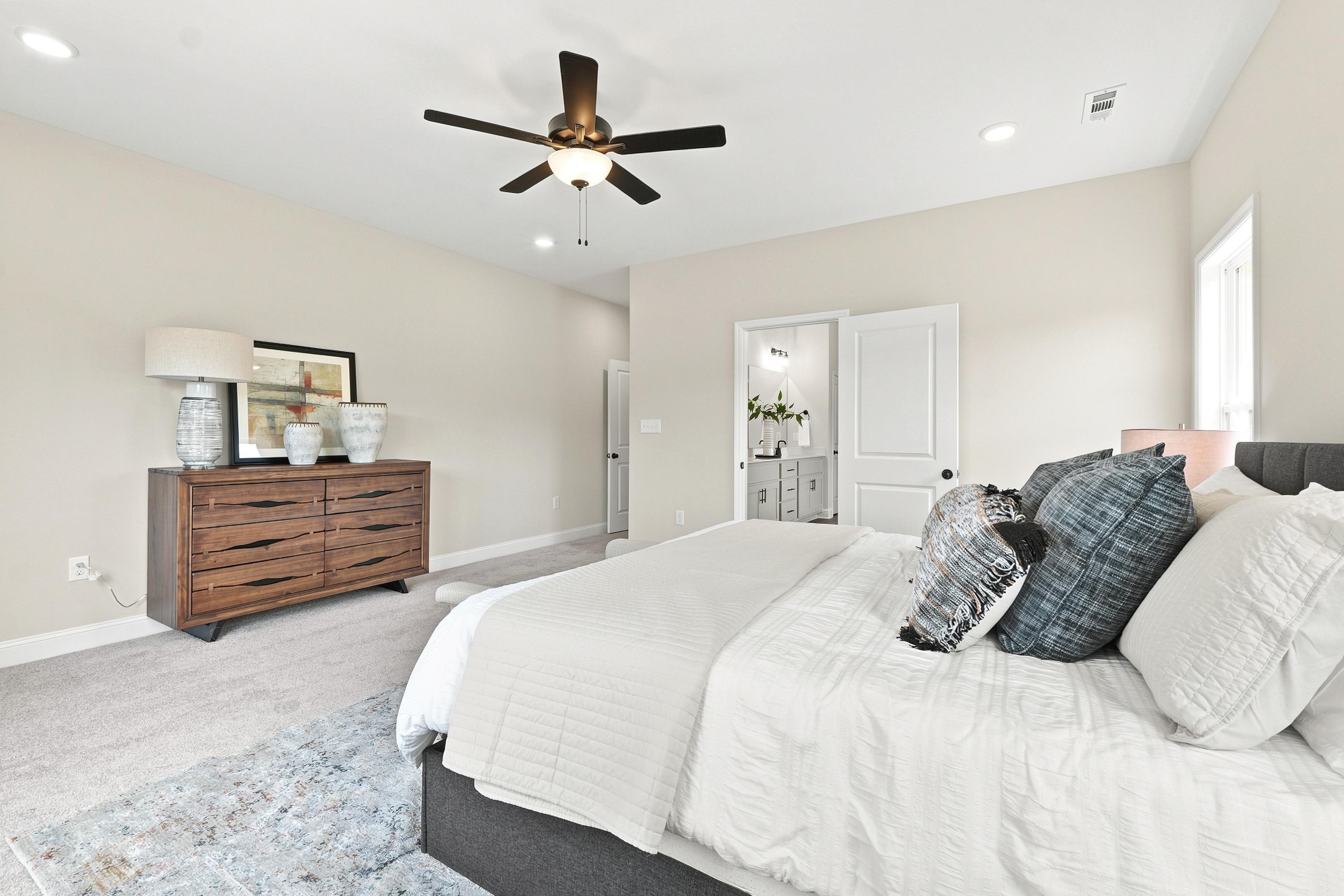 Spacious primary bedroom at Riverton Preserve in Huntsville, AL by Davidson Homes featuring a modern dresser and ensuite bath.