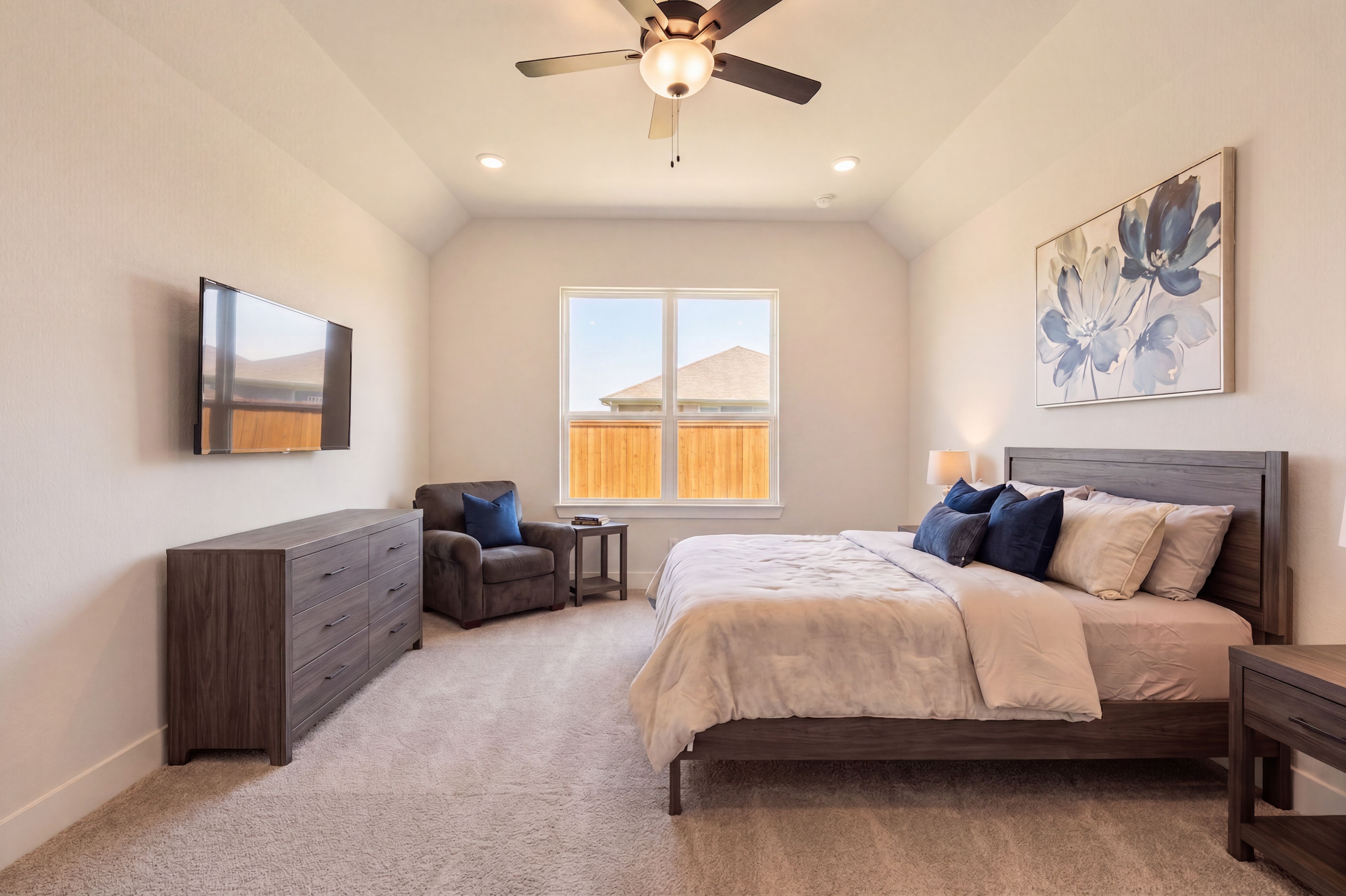 primary bedroom with queen sized bed, dark colored furniture and bright window