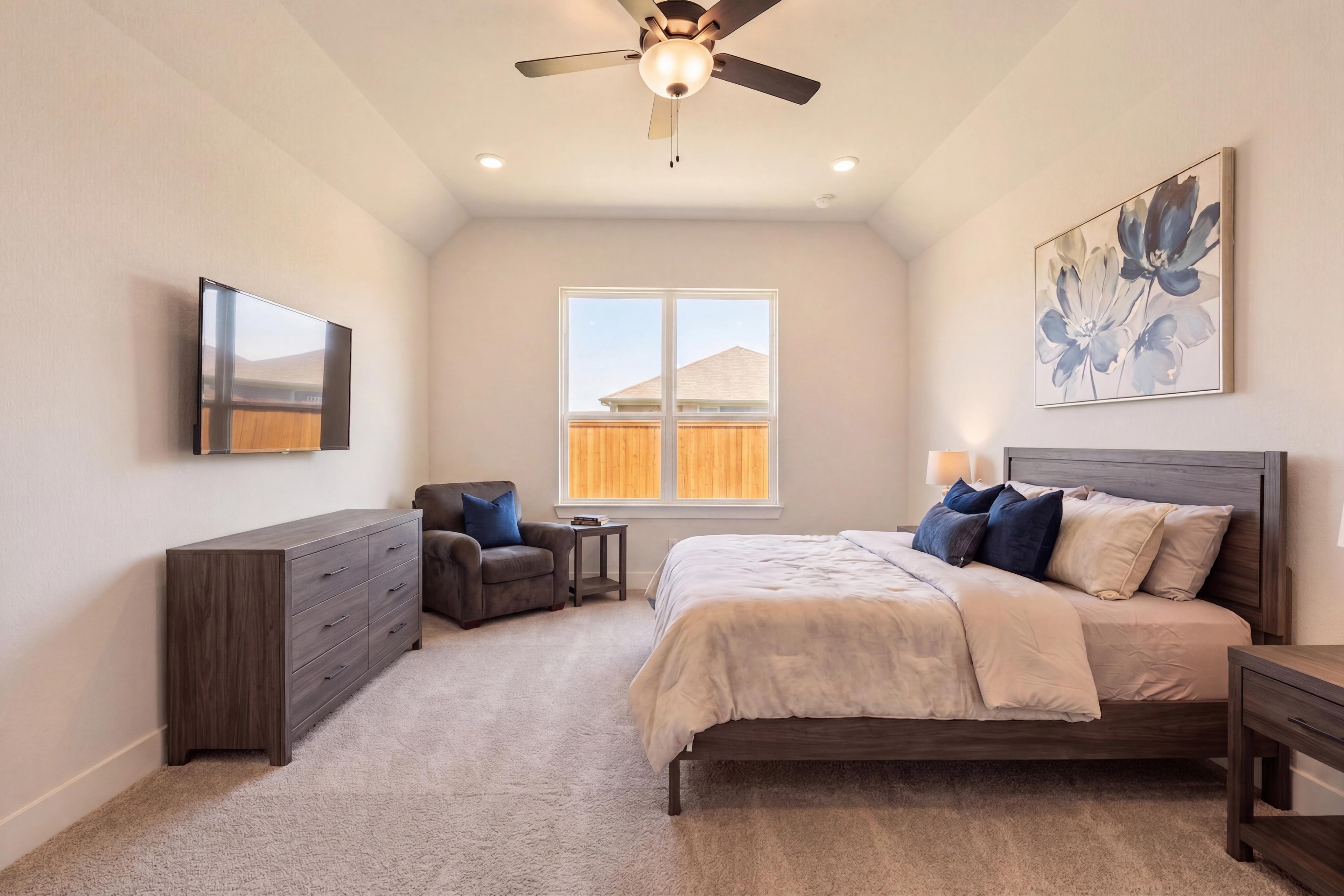 primary bedroom with queen sized bed, dark colored furniture and bright window