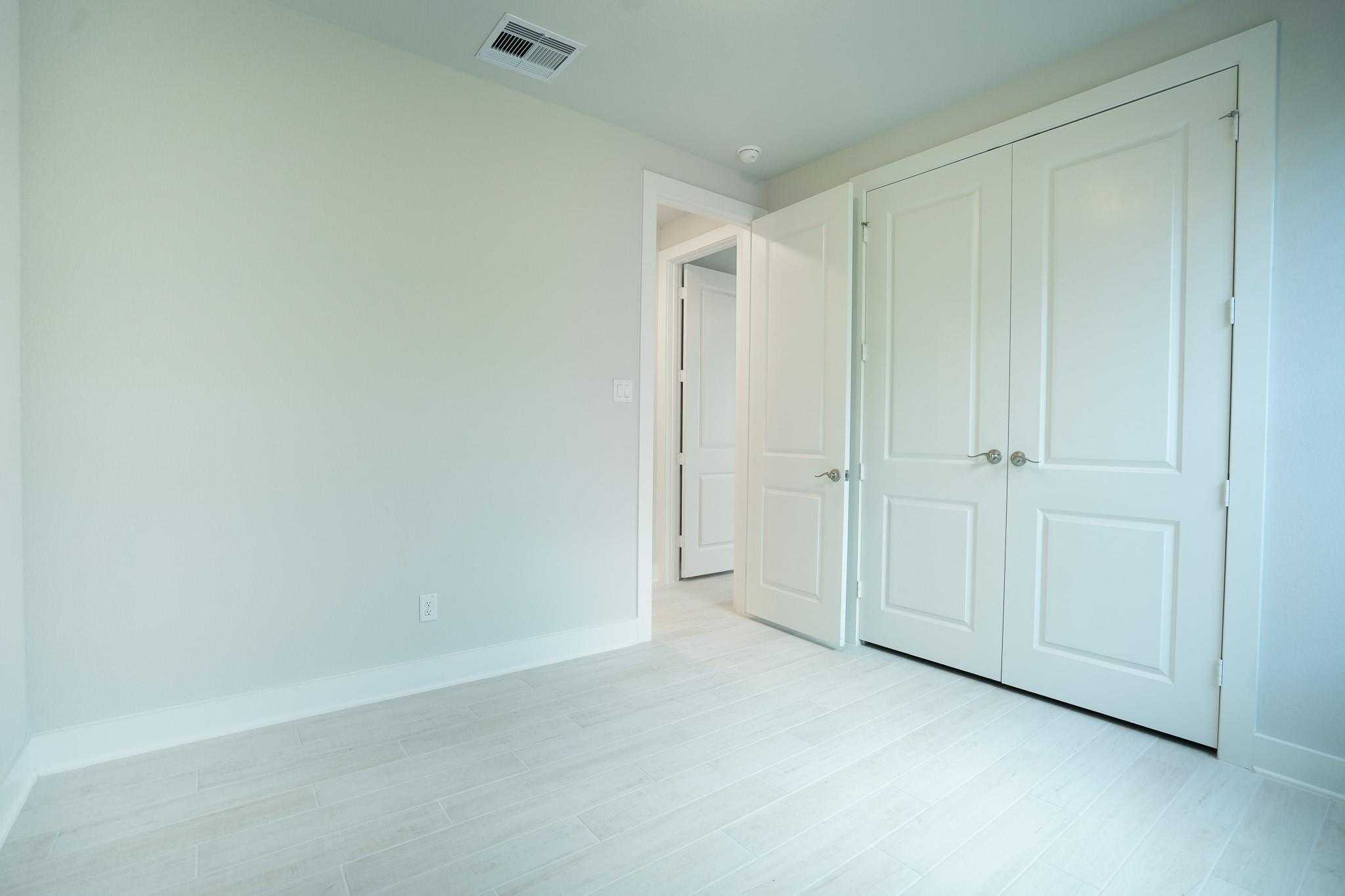 Spacious secondary bedroom with white double closet doors and bathroom access in Davidson Homes The Edward C, Lago Mar, Texas City