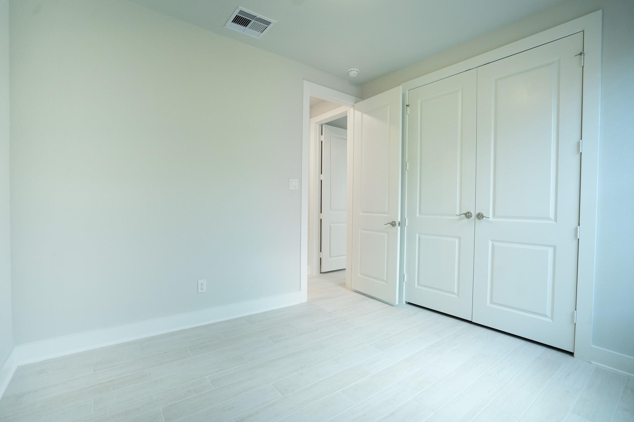Spacious secondary bedroom with white double closet doors and bathroom access in Davidson Homes The Edward C, Lago Mar, Texas City