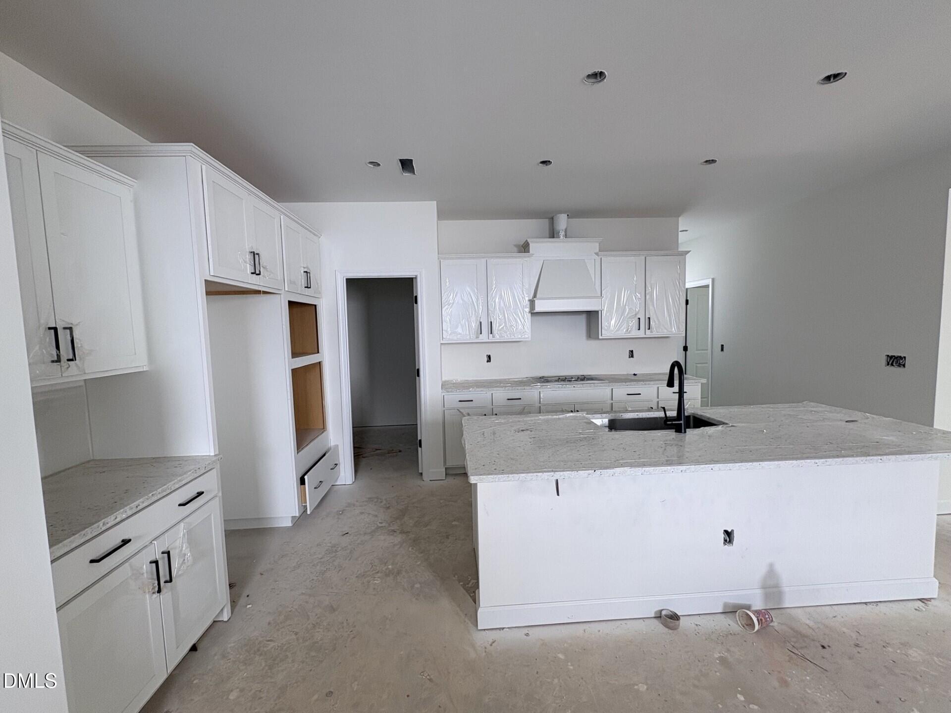 White kitchen with granite countertops, oversized island, and black hardware in Davidson Homes The Adalynn A, Zebulon NC