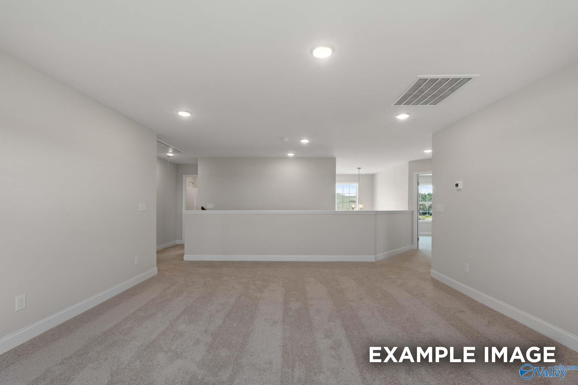 Spacious open living area with upstairs balcony railing, neutral walls, carpet floors in 5-bedroom Madison A home, Toney Alabama
