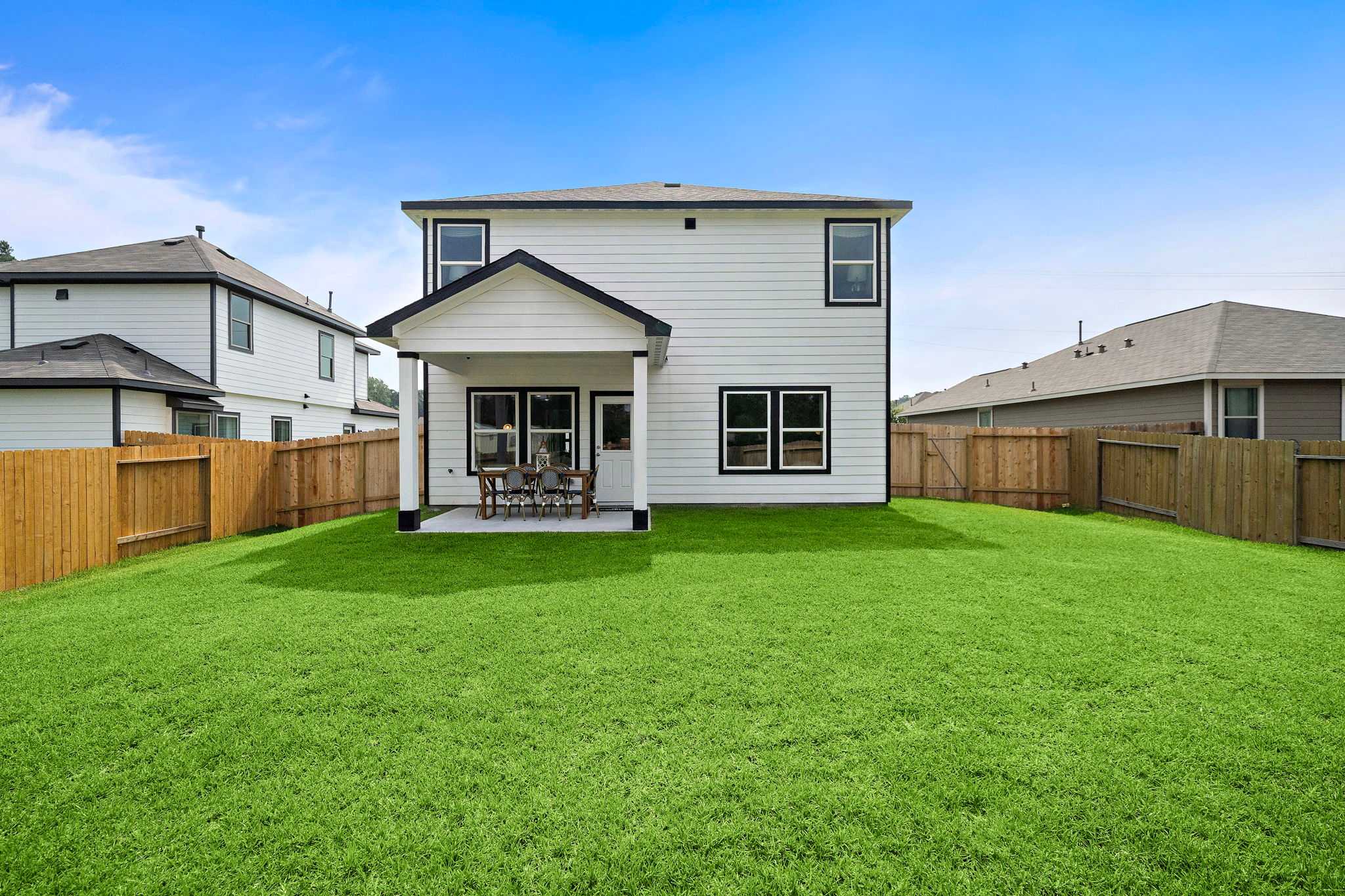 Spacious backyard with covered patio at Liberty Estates in Cleveland Texas by Davidson Homes featuring lush green lawn and outdoor seating