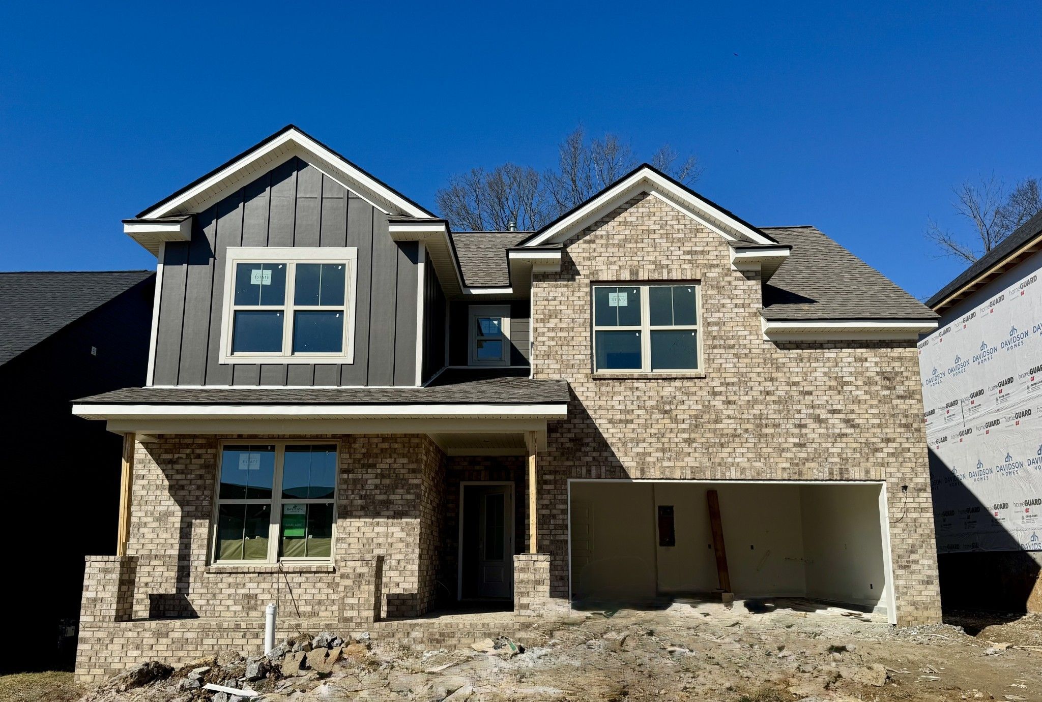 Two-story brick home with gray siding, gabled roof, and open two-car garage in Woods Crossing, Gallatin, Tennessee