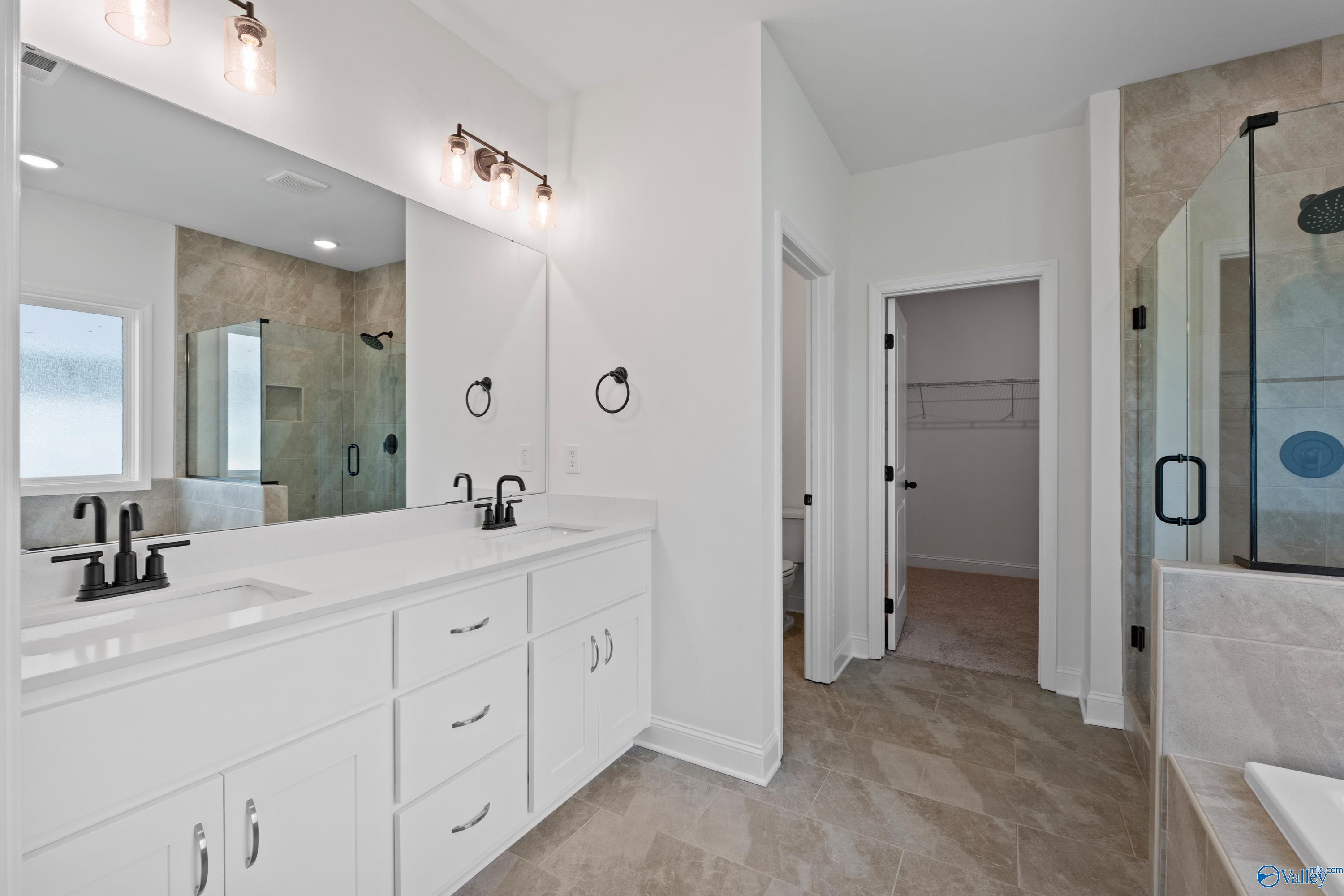 Modern master bathroom with double vanity, frameless glass shower, and walk-in closet in Davidson Homes The Rockford B, Toney, Alabama