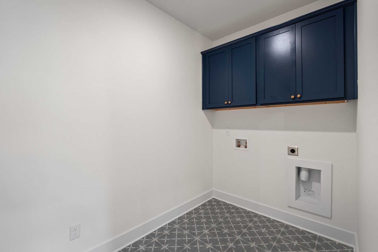 Modern laundry room with navy shaker cabinets, white utility sink, outlets, and geometric gray tile floor in Davidson Homes The Ridgeport, Gallatin, TN