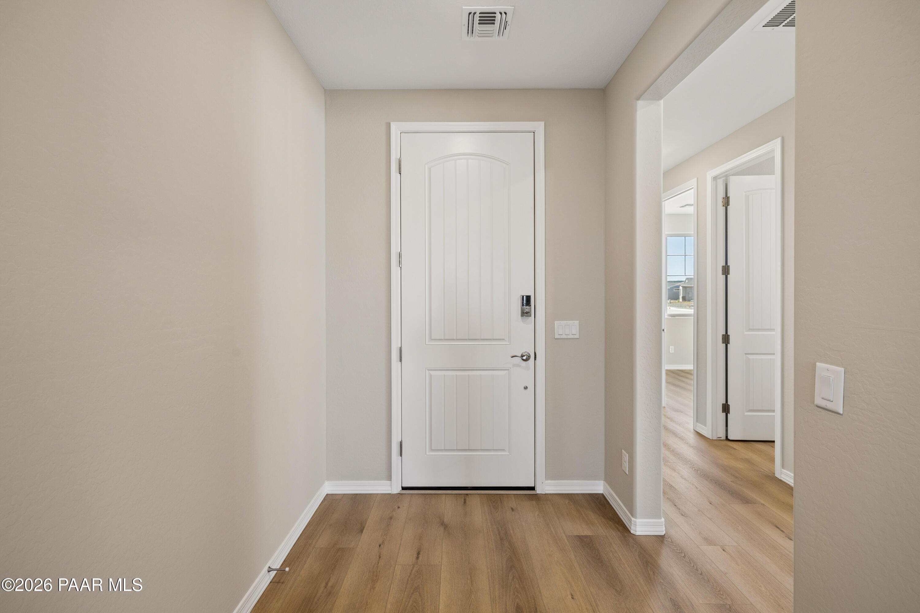 Welcoming entry foyer with white arched door, beige walls, hardwood floors in Davidson Homes The Harmony A, Prescott Valley, Arizona