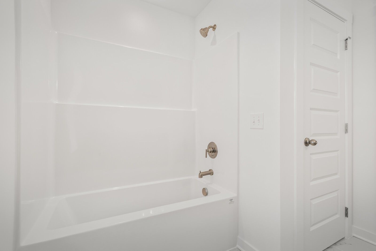 Modern white bathroom with tiled shower, freestanding tub, brass fixtures in Davidson Homes The Gordon C, White House, TN