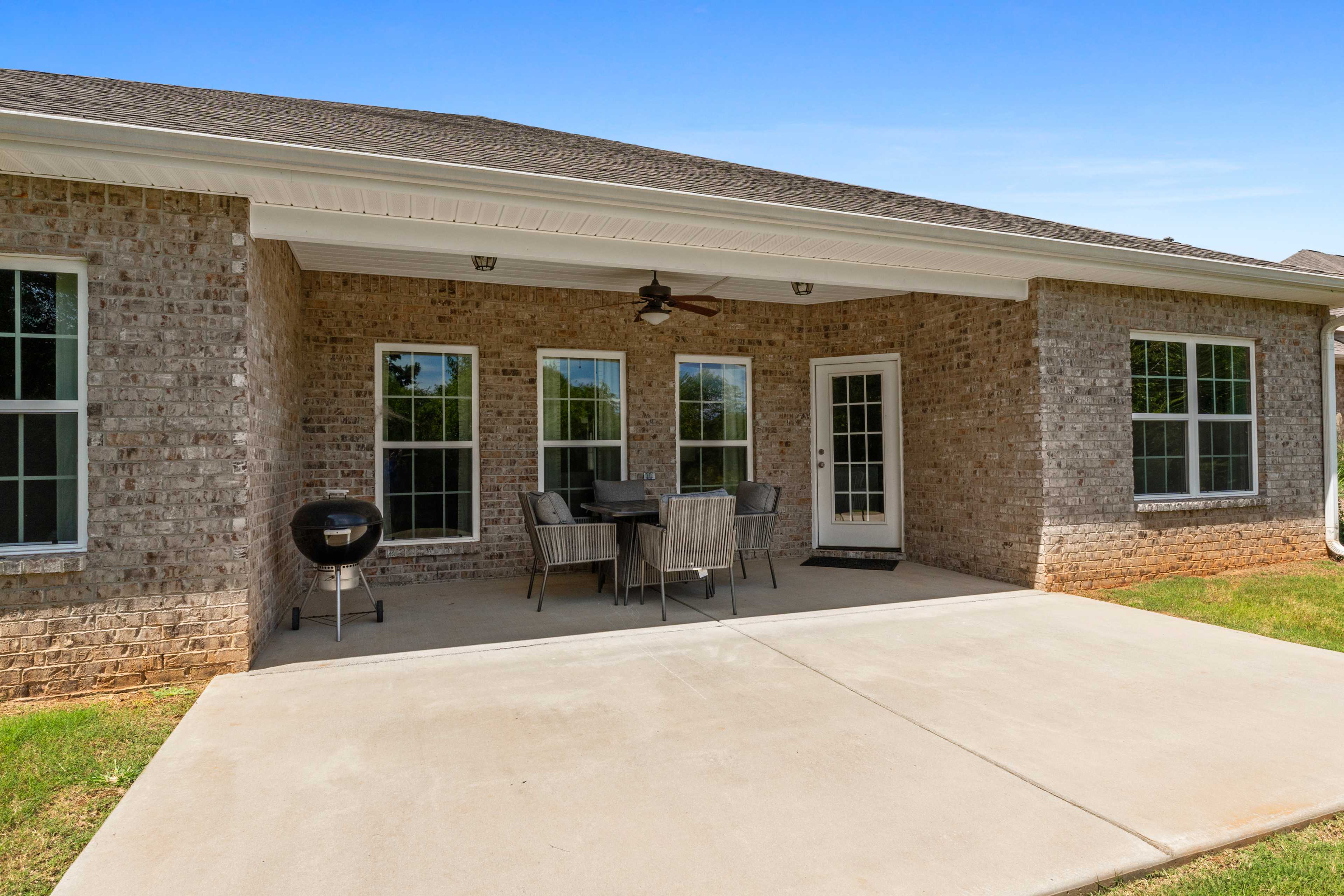 Spacious covered patio at Kendall Downs in Toney Alabama with brick home, ceiling fan, dining set and grill