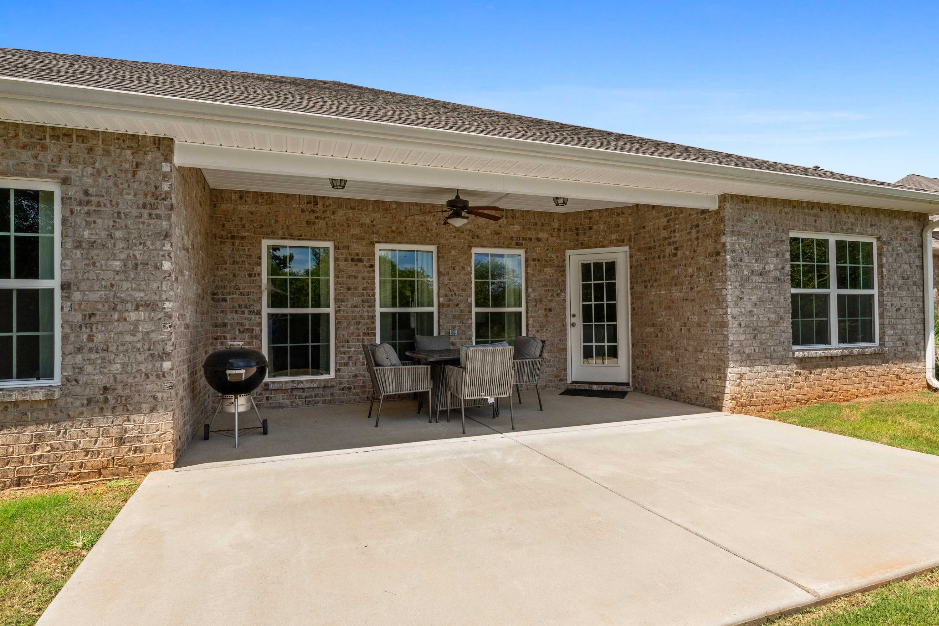 Spacious covered patio at Kendall Downs in Toney Alabama with brick home, ceiling fan, dining set and grill